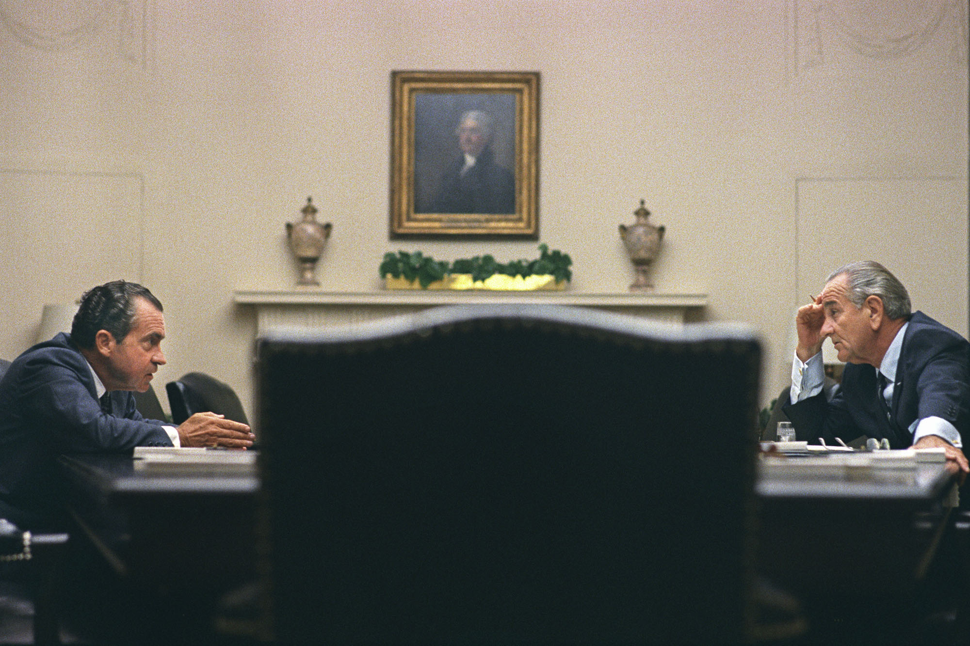 President Lyndon B. Johnson, right, and Richard Nixon, left talk across from each other at a table
