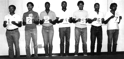 Men in a lineup holding numbers