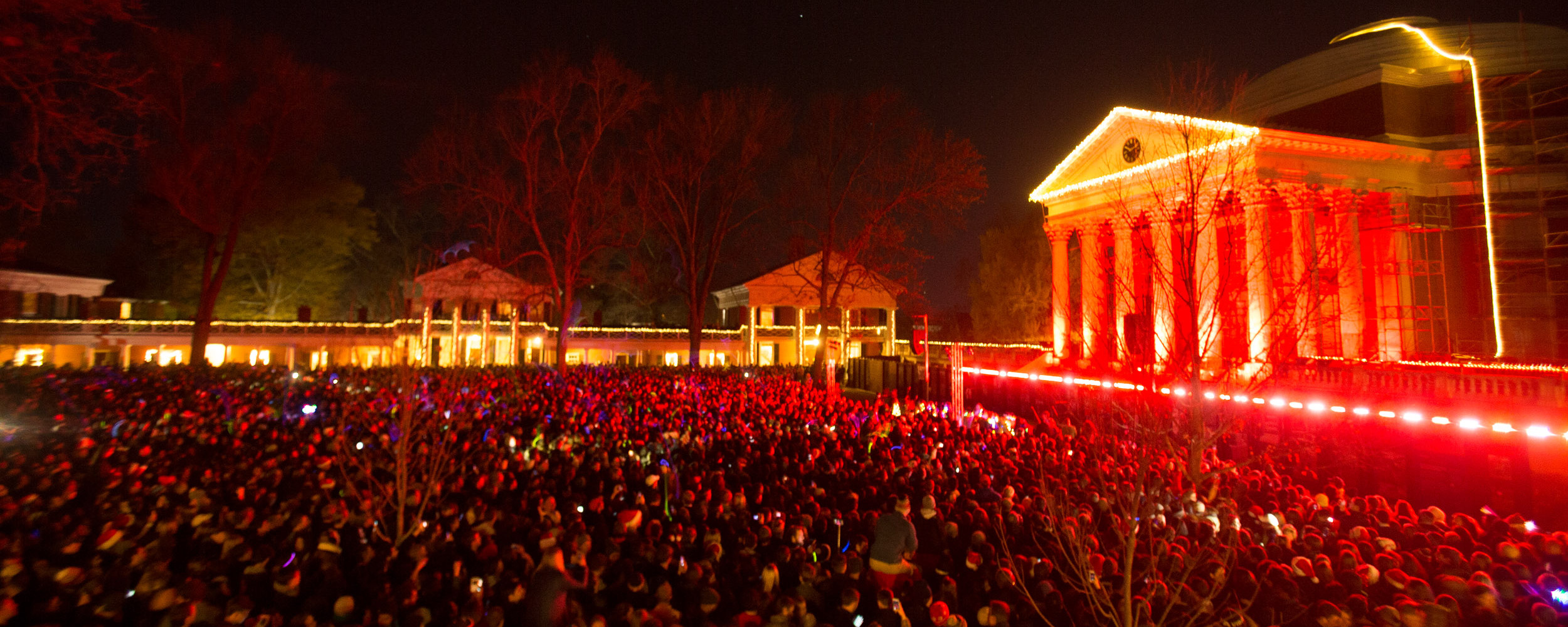 Thousands of students on the Lawn with colorful lights as the Rotunda is lit up