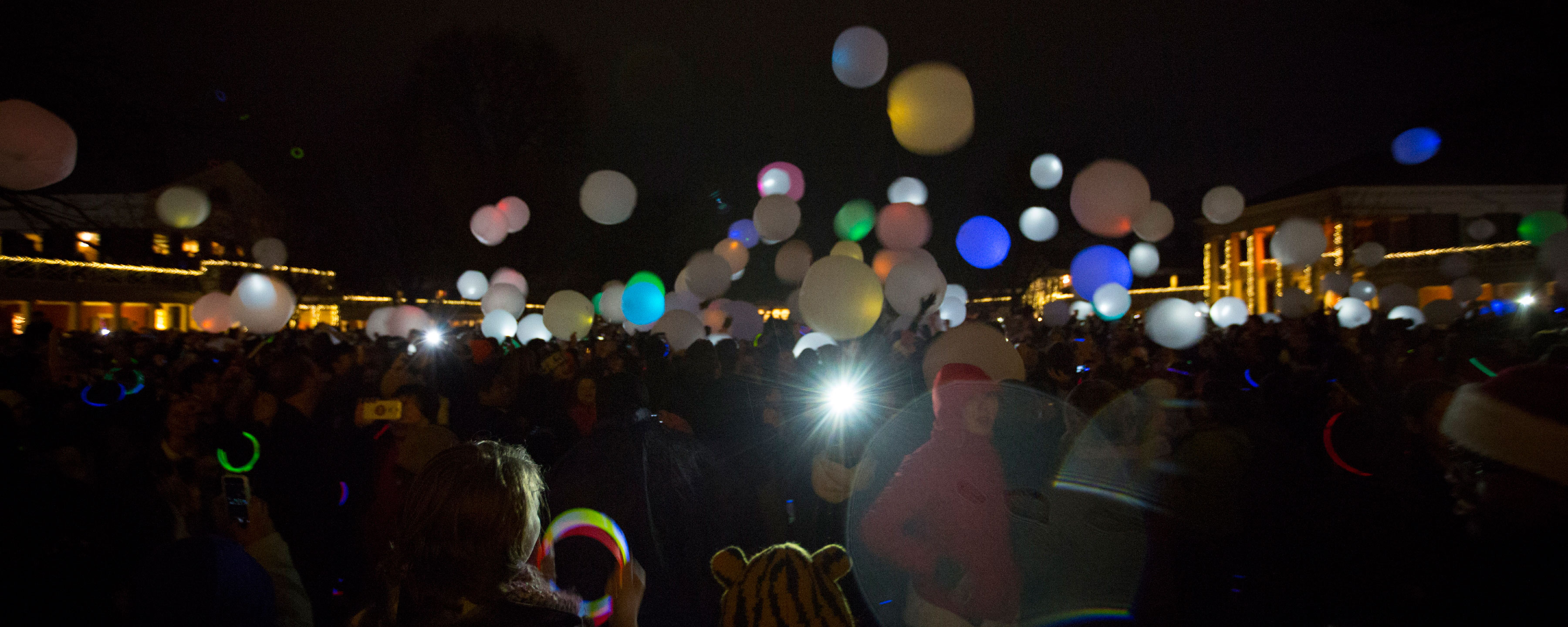Glow in the dark balloons fly high over a crowd on the lawn