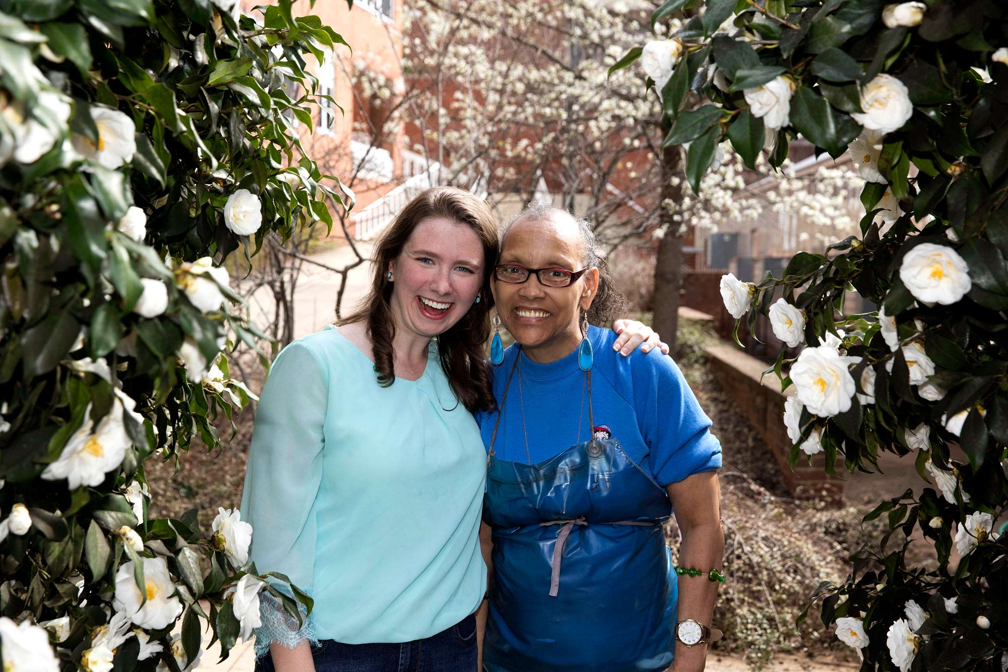 Maeve Curtin and Linda Miles stand between flowers smiling for the camera