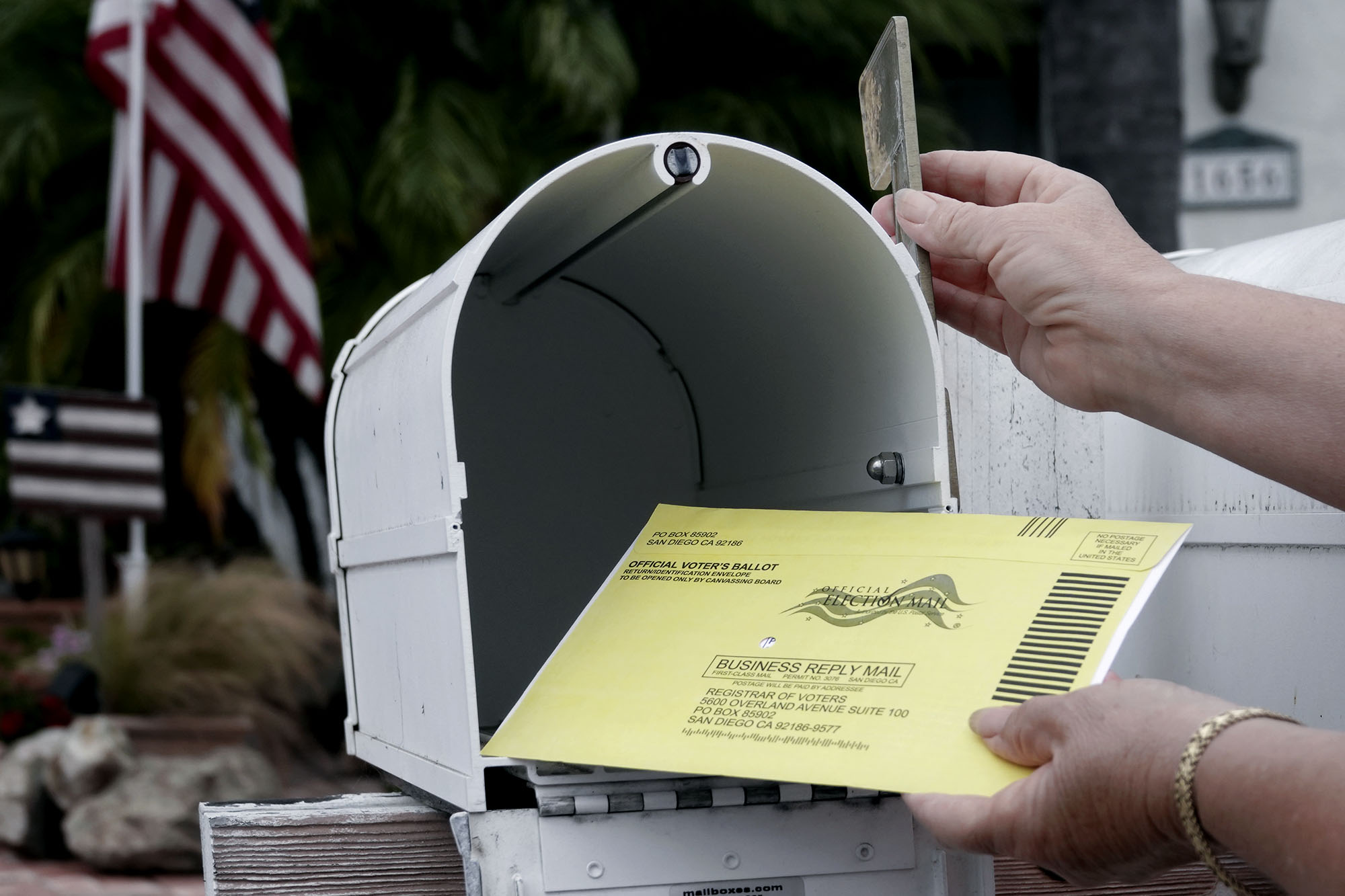 Person placing their election ballot in a mailbox and raising the flag