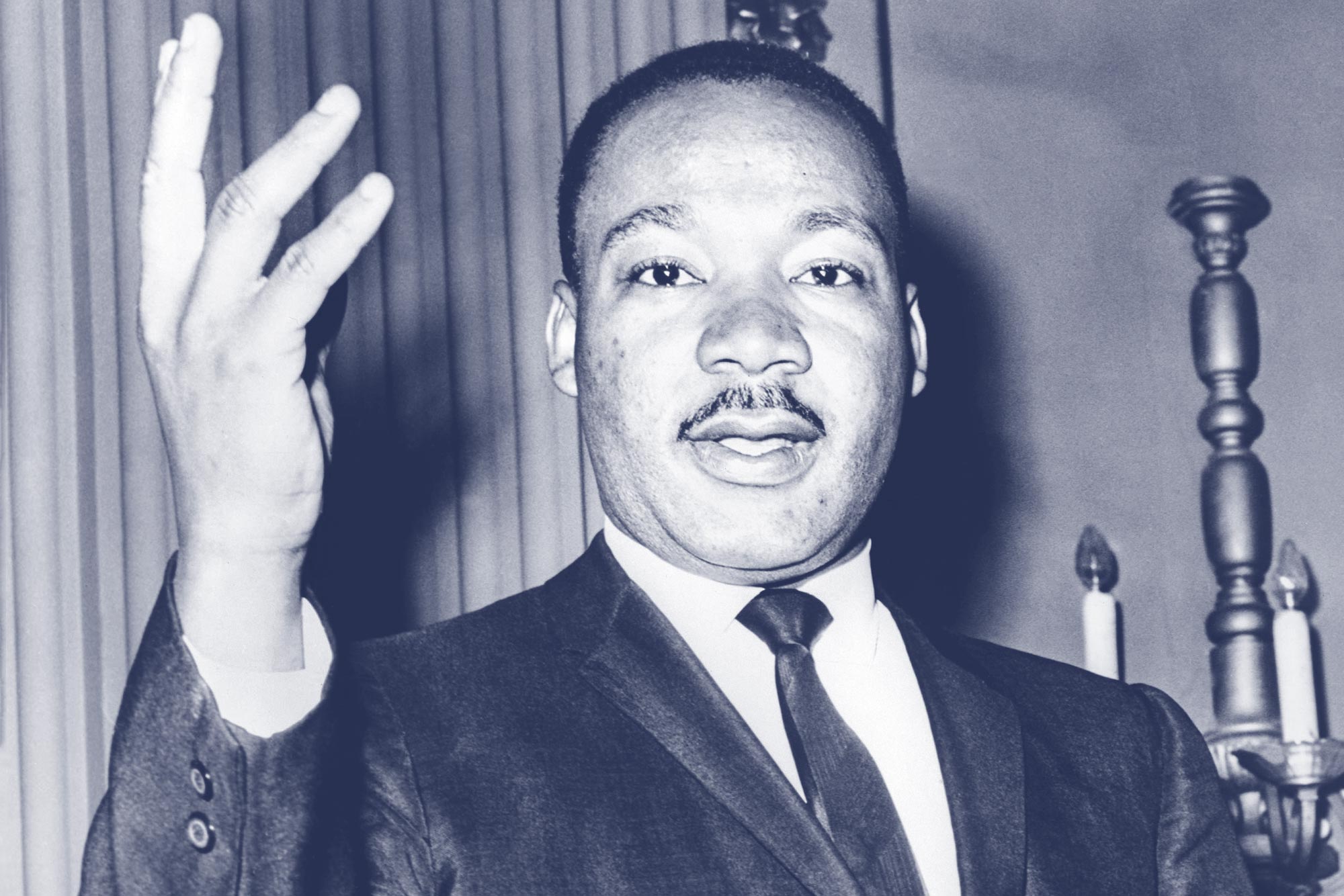 Black and White image of the Dr. Martin Luther King holding his right hand up