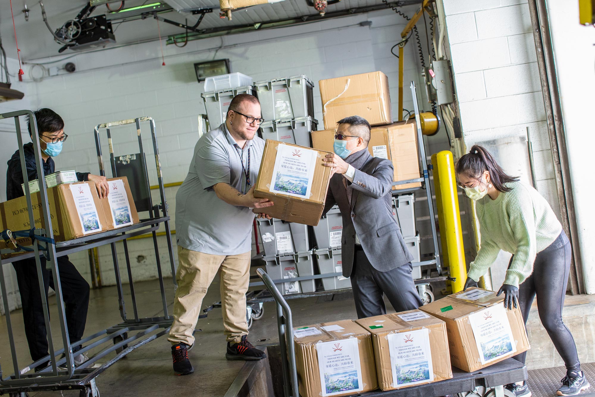 Group of volunteers placing boxes of mask donations onto a dolly