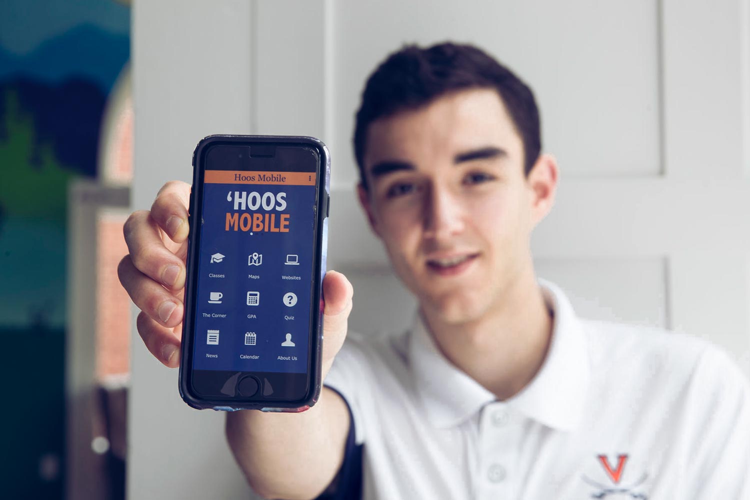 Matthew Wajsgras holds up his phone with the 'Hoos Mobile app opened