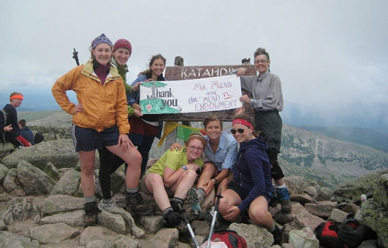 Group of people standing at the Appalachian Trail Mount Katahdin sign holding a thank you sign up