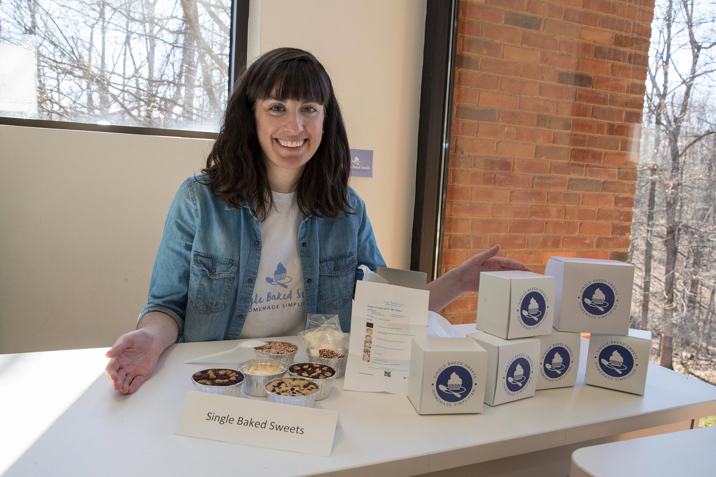Melissa Stefaniak sits at a table with boxes and single baked sweets