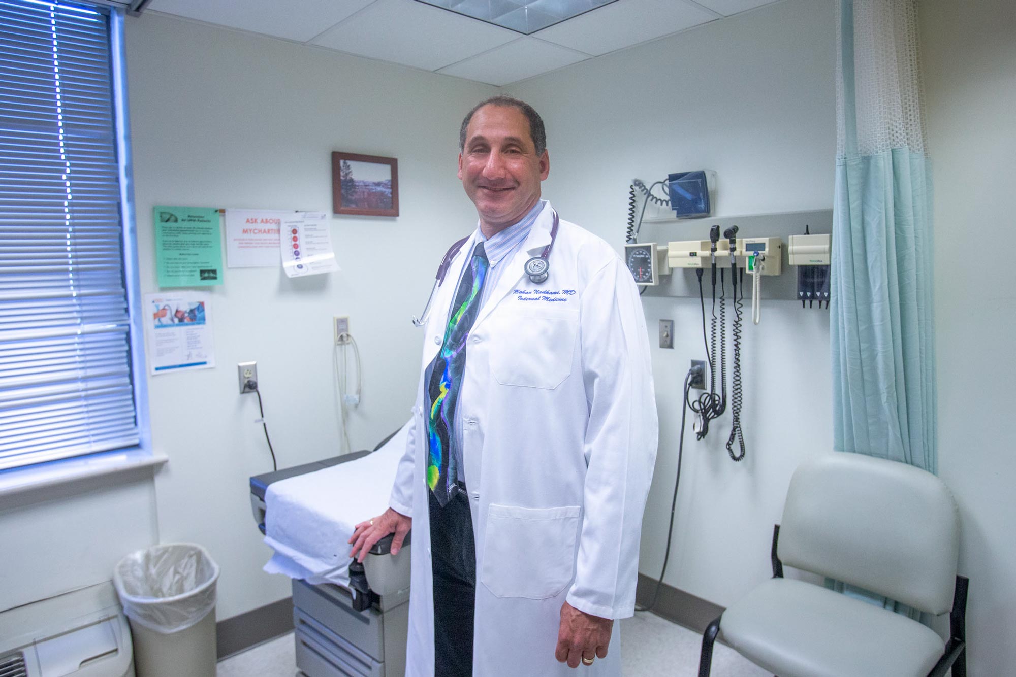 Dr. Mohan Nadkarni  standing in a hospital room looking at the camera