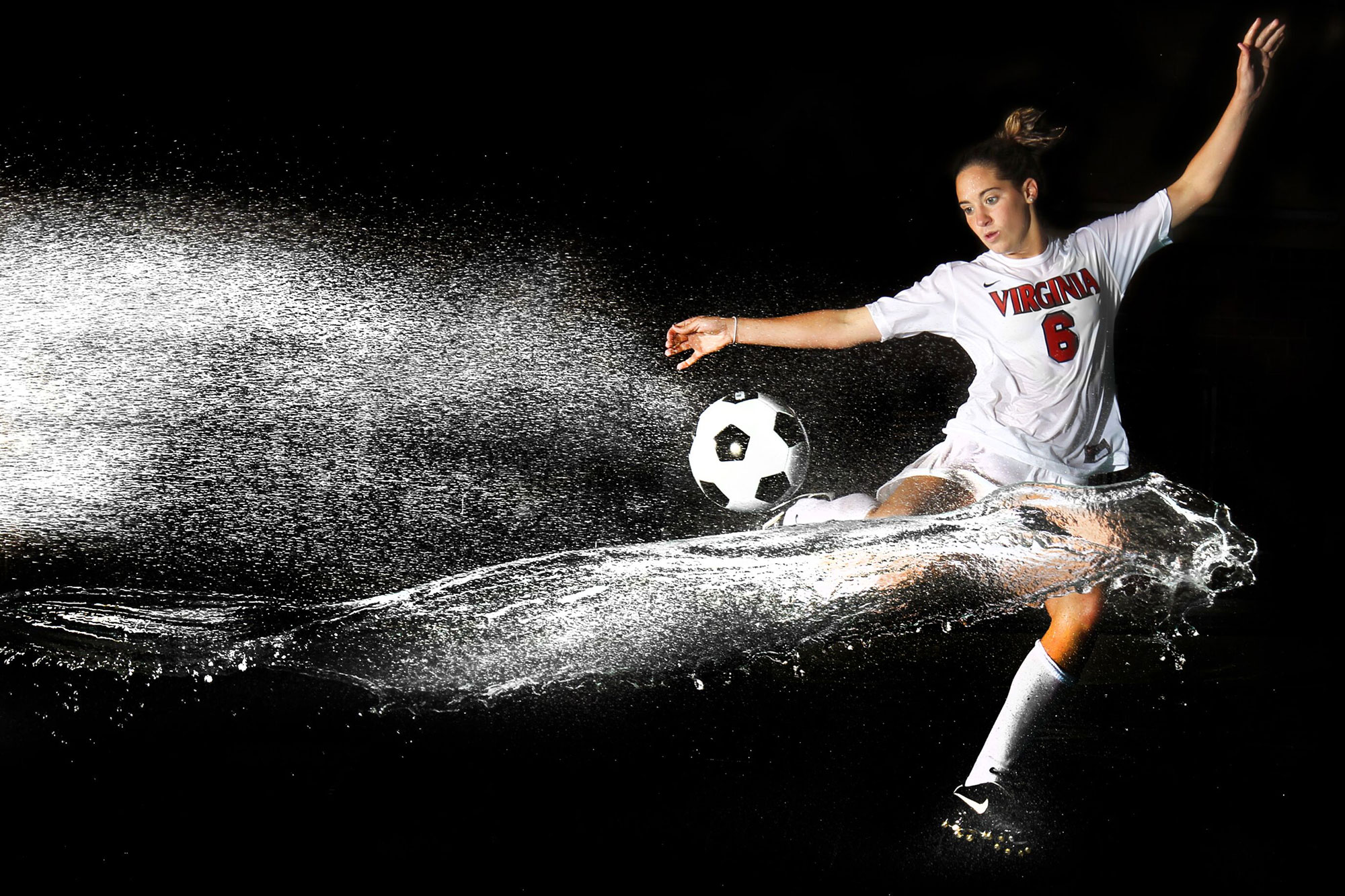 Morgan Brian kicking a soccer ball while water splashes
