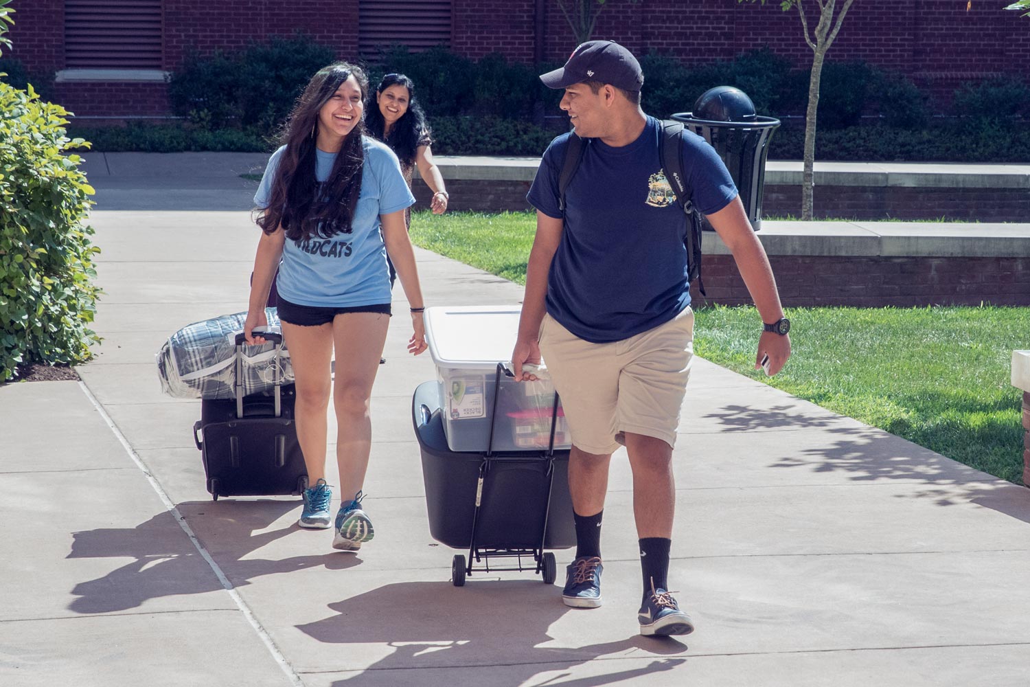 Student with their parents pulling rolling luggage to move into a dorm