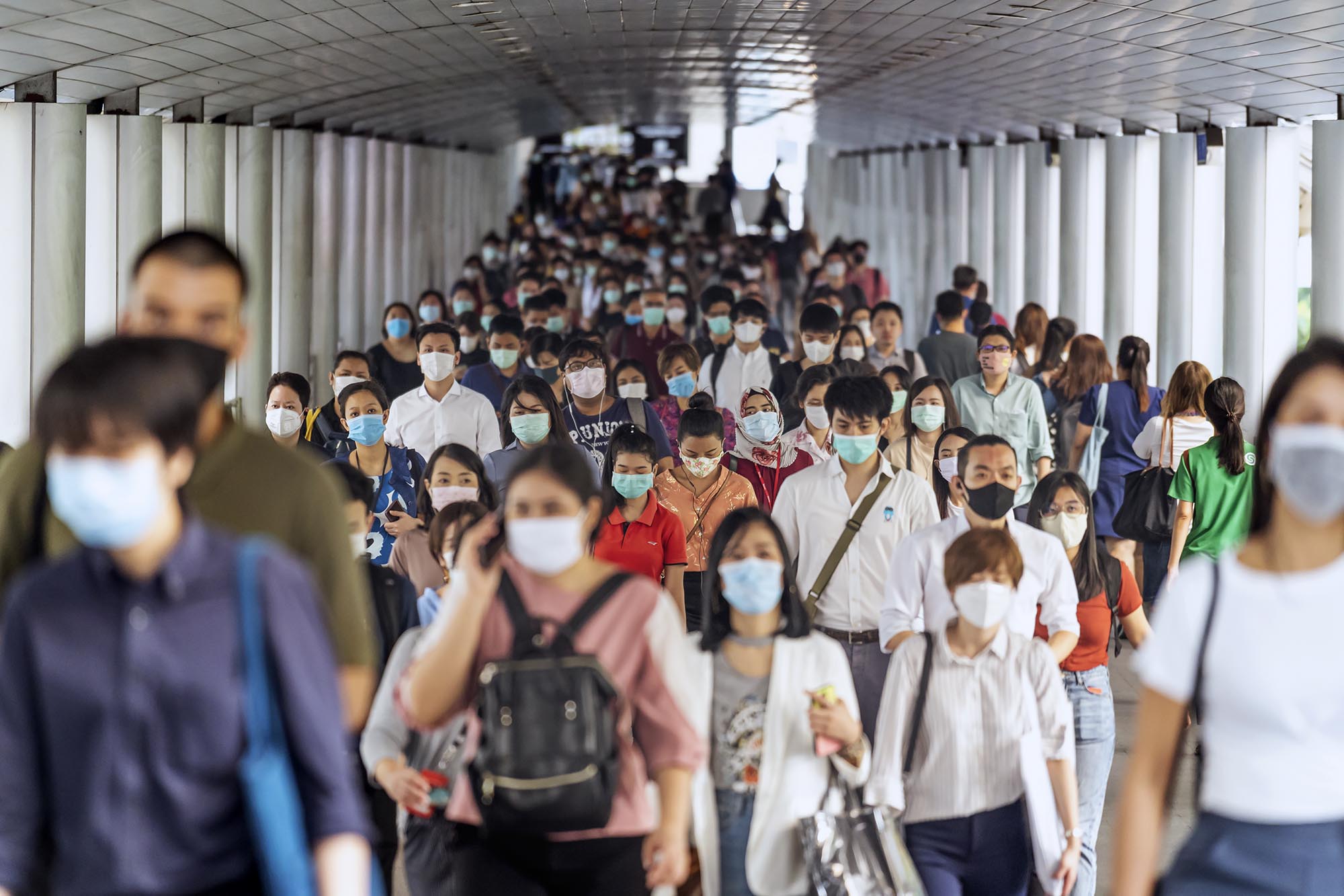 Hallway filled with people wearing masks walking