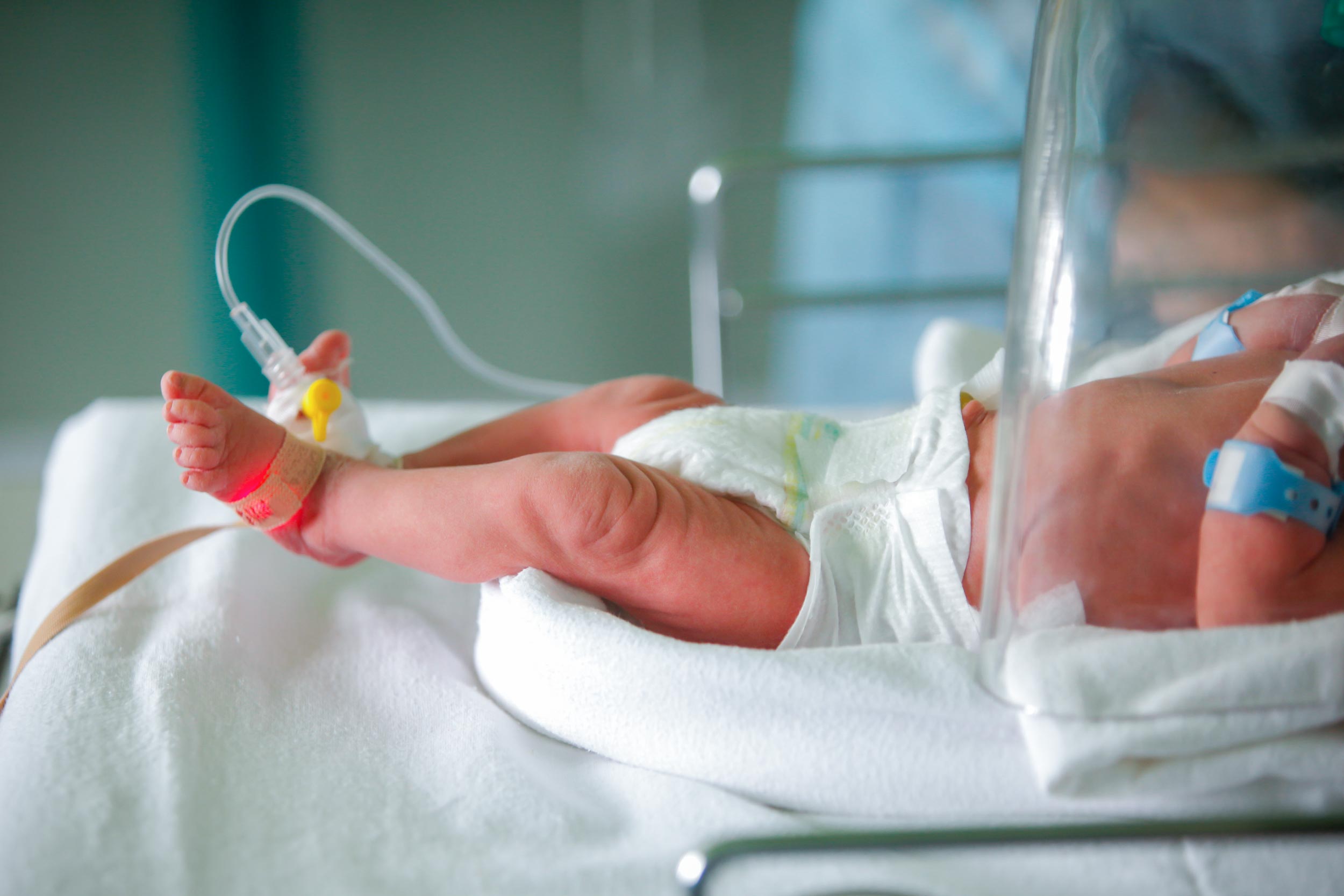 Baby in the NICU with tubes and a pulse ox attached to them