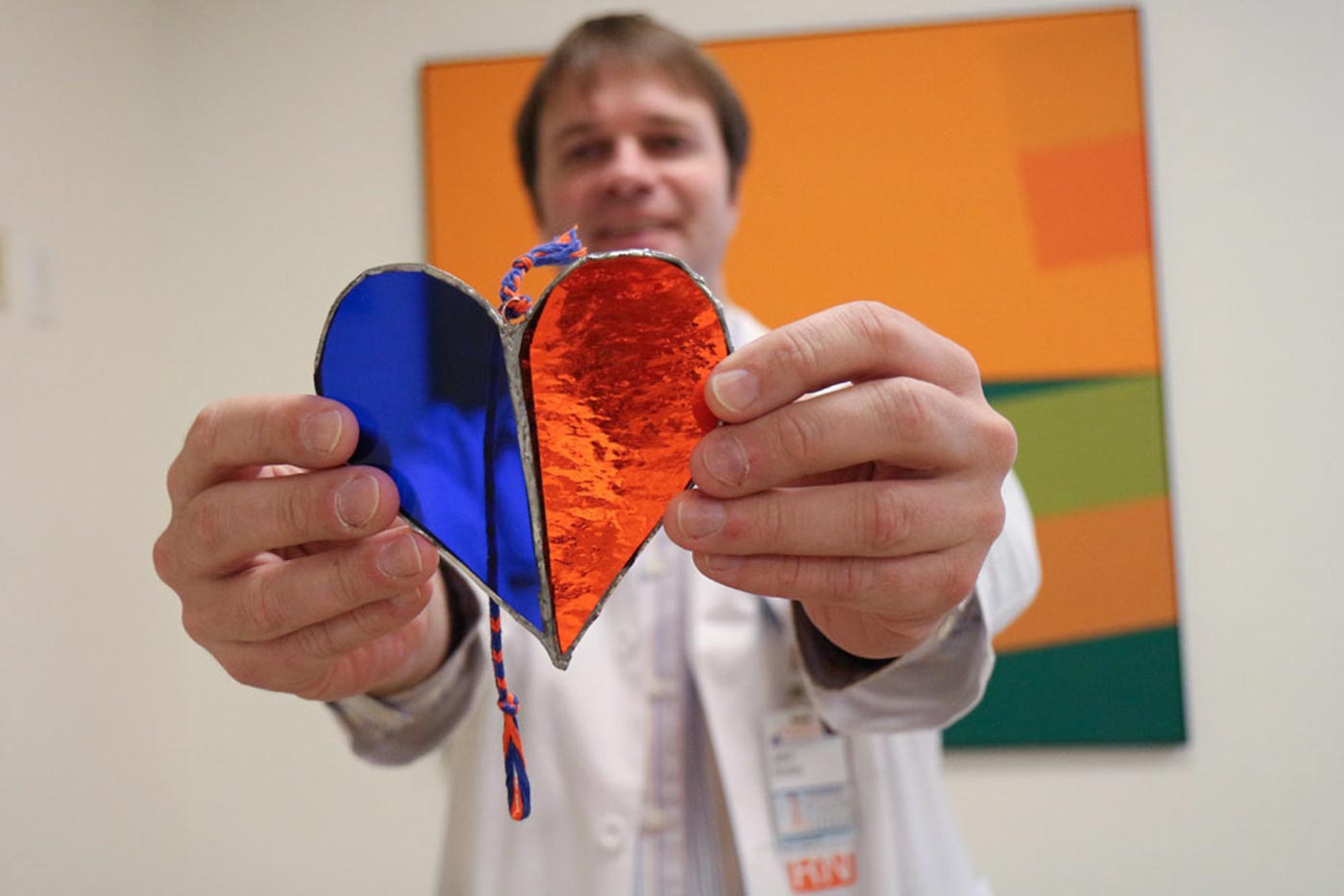 John Smiley holds a heart made of orange and blue glass