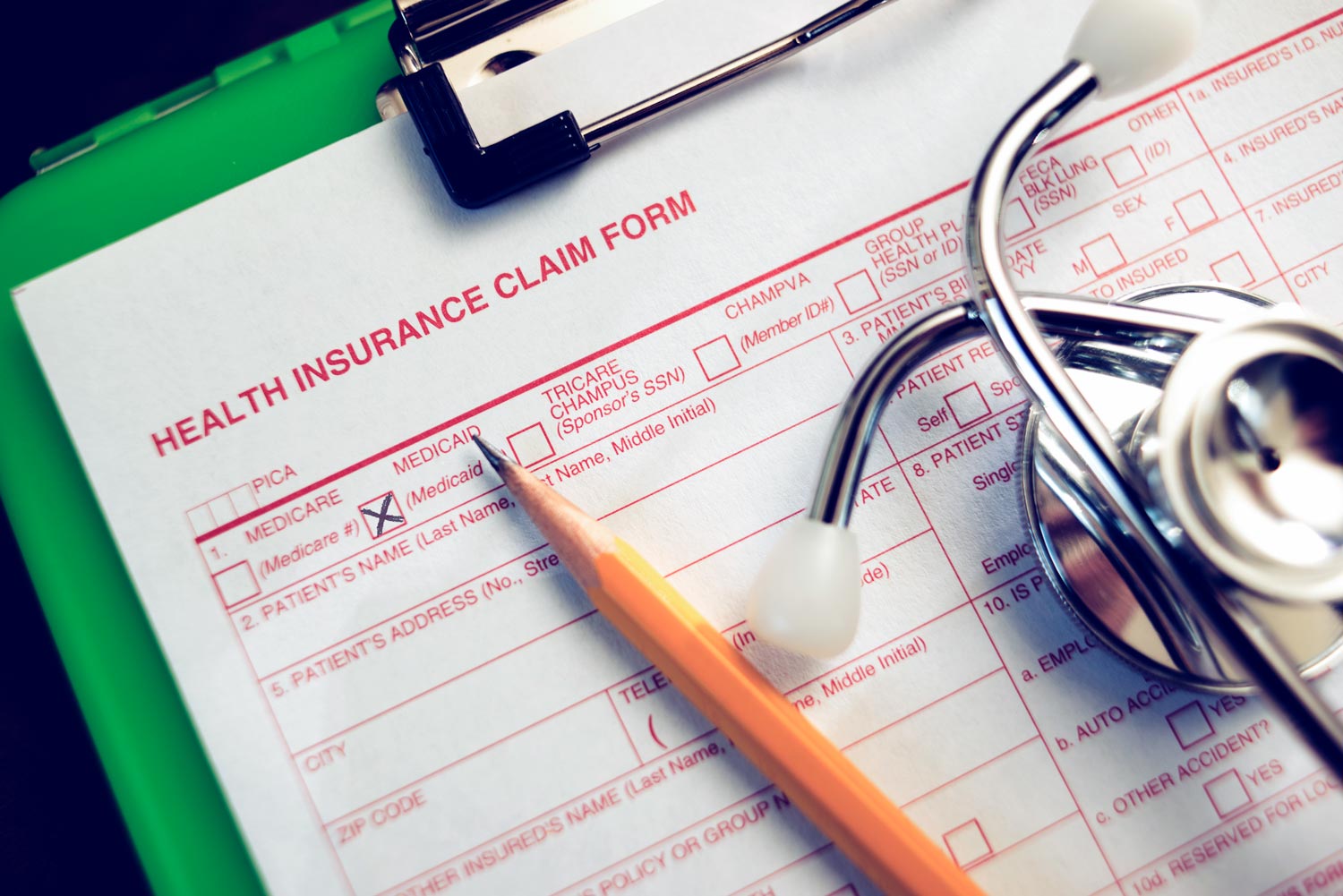 Health Insurance Claim Form with a pencil on it and stethoscope