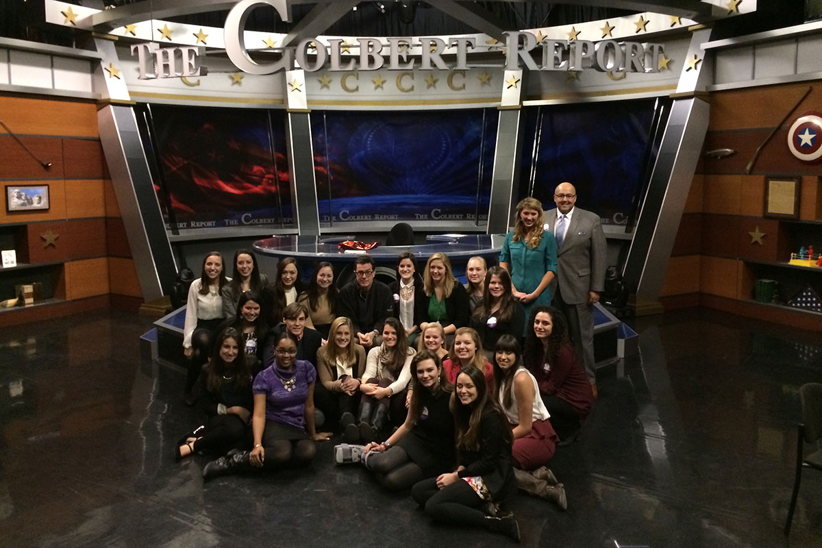 Stephen Colbert sits with a group of students on set of his show to take a group photo