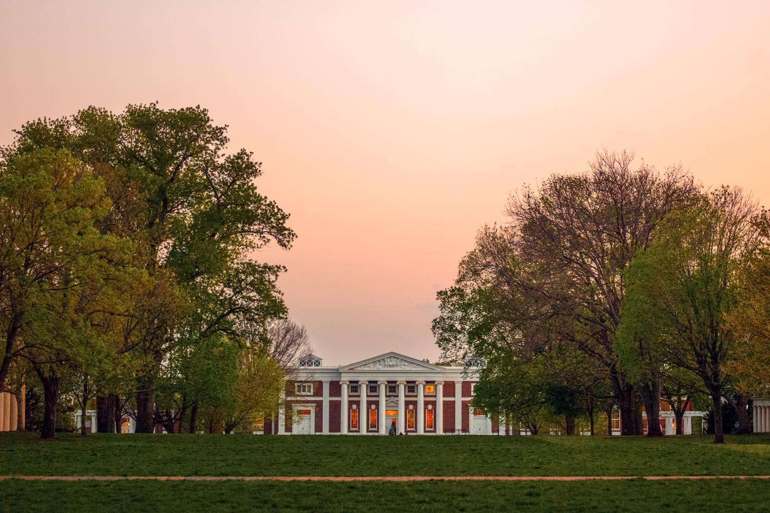 Cabell hall from the lawn with a pink orange sunset behind it