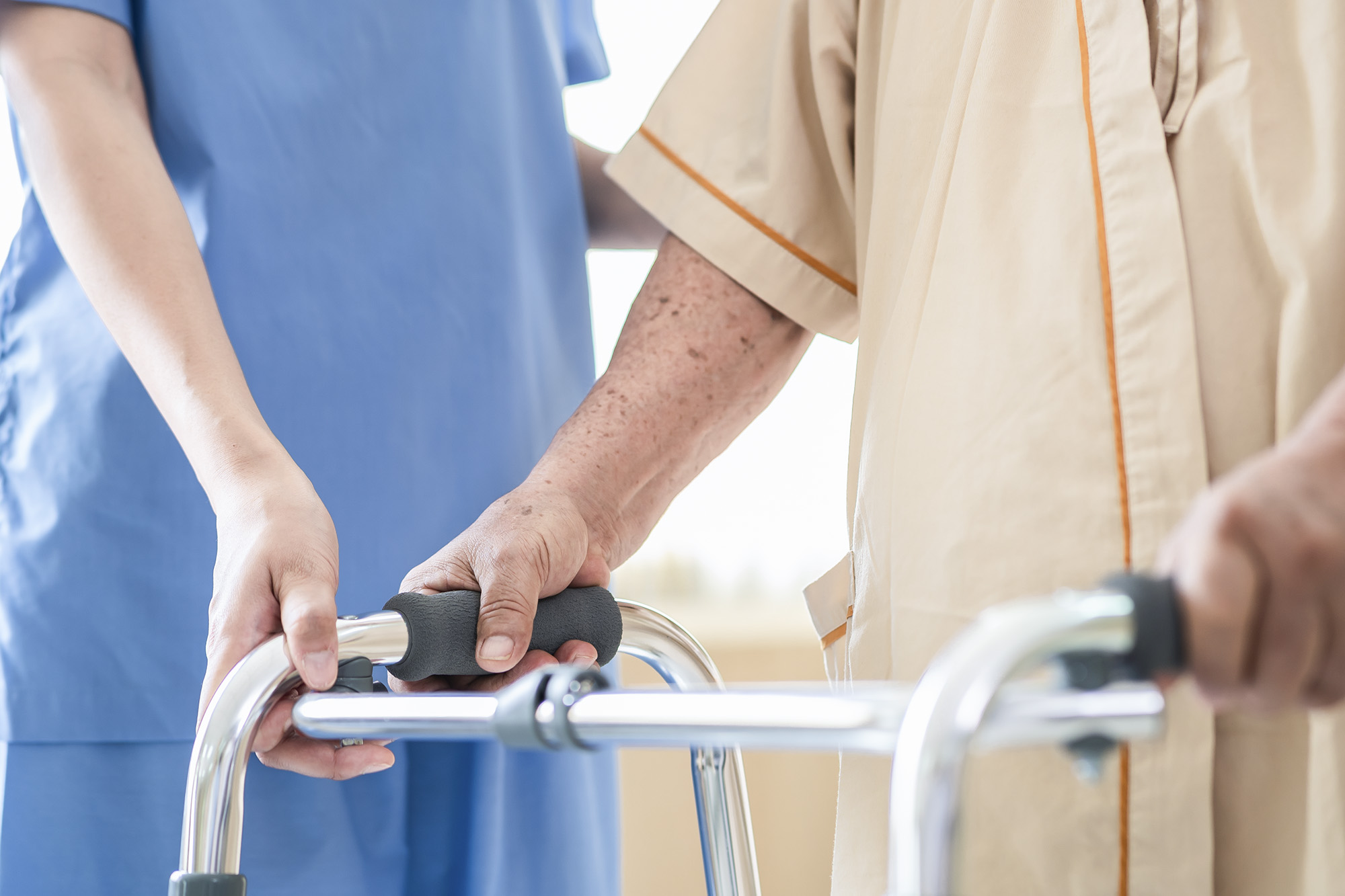 Healthcare professional helping an elderly person with a walker