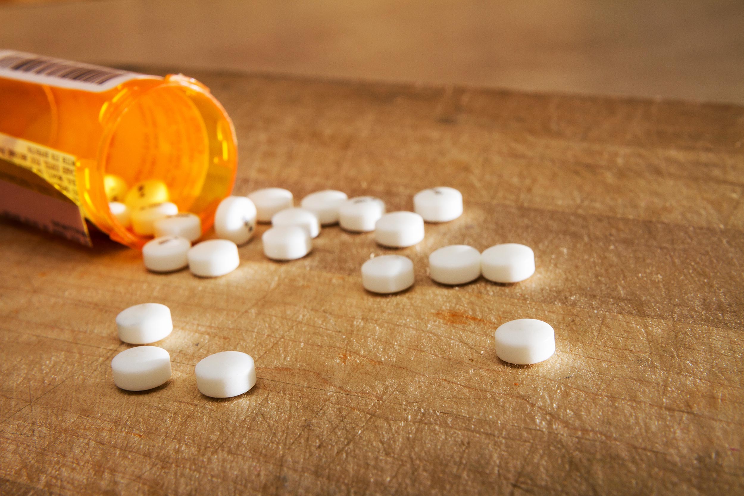 Opioids on a table coming out of a pill bottle