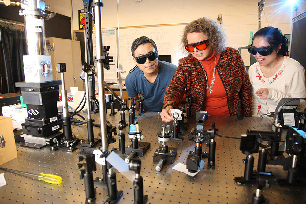 Pamela Norris works with two students with a machine