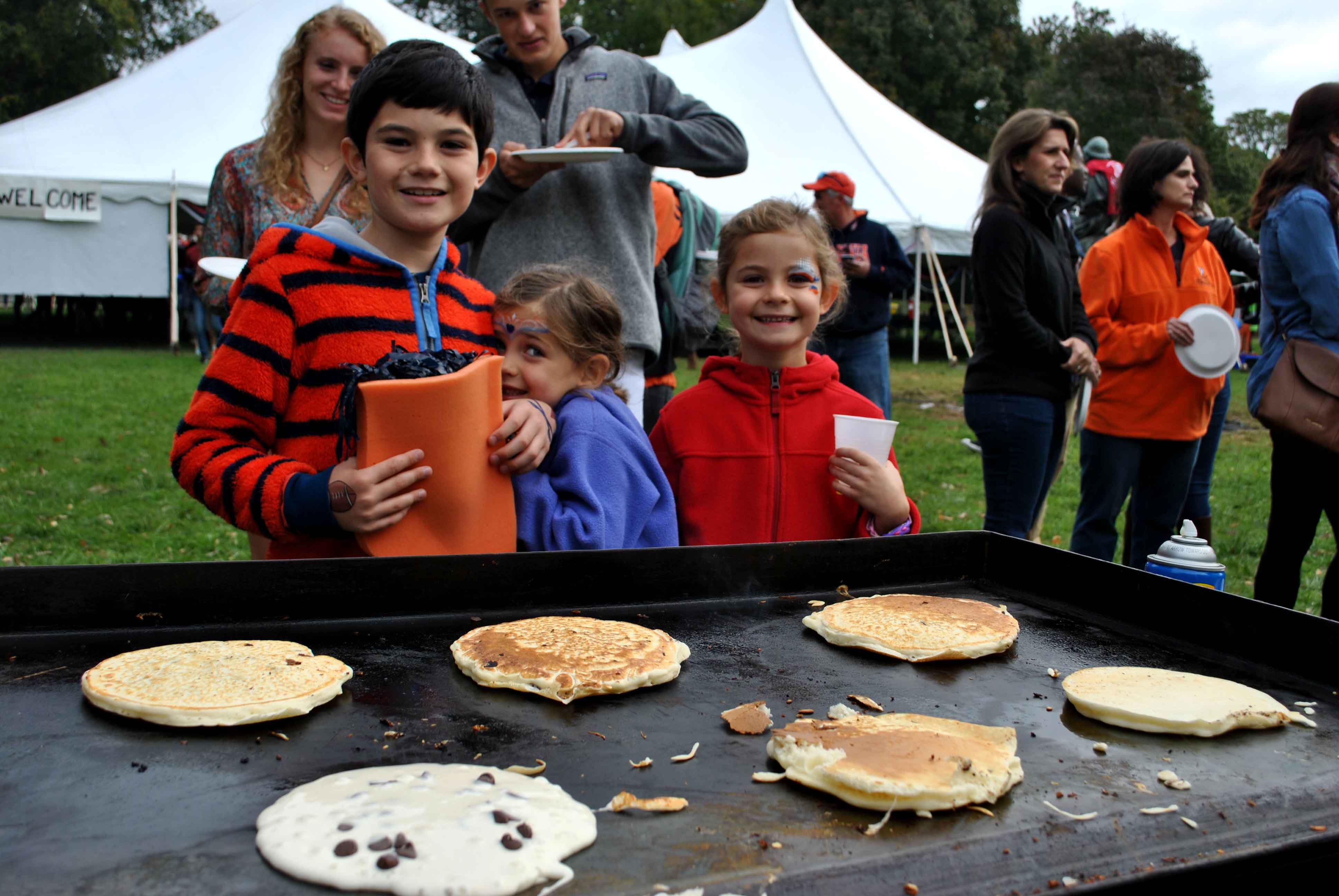 Children standing at a griddle waiting for pancakes