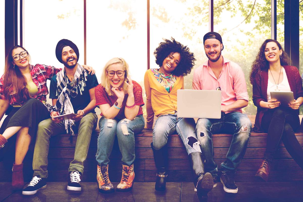 Group of students sitting on a bench smiling for the camera