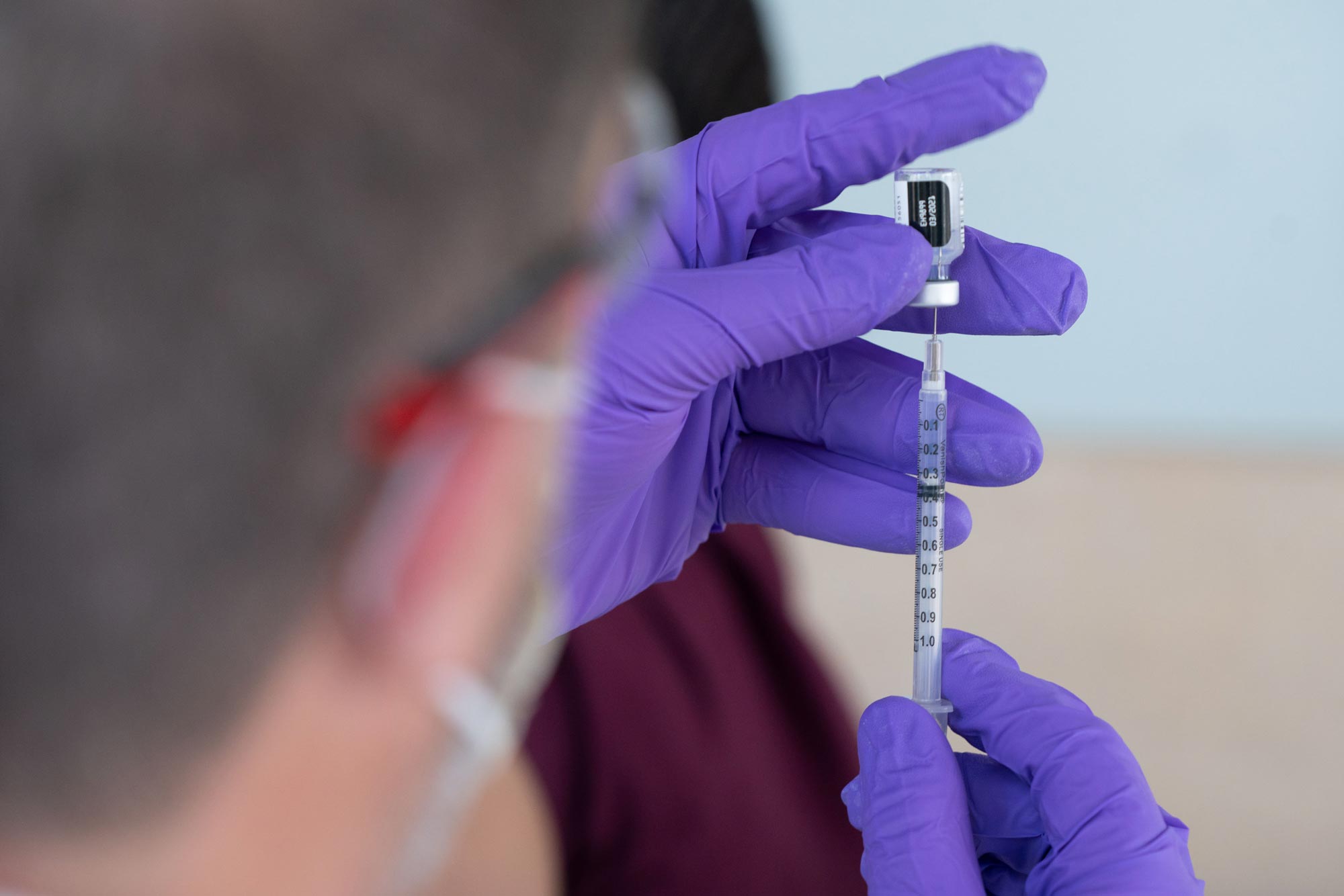 Healthcare worker drawing up covid-19 vaccine in a syringe