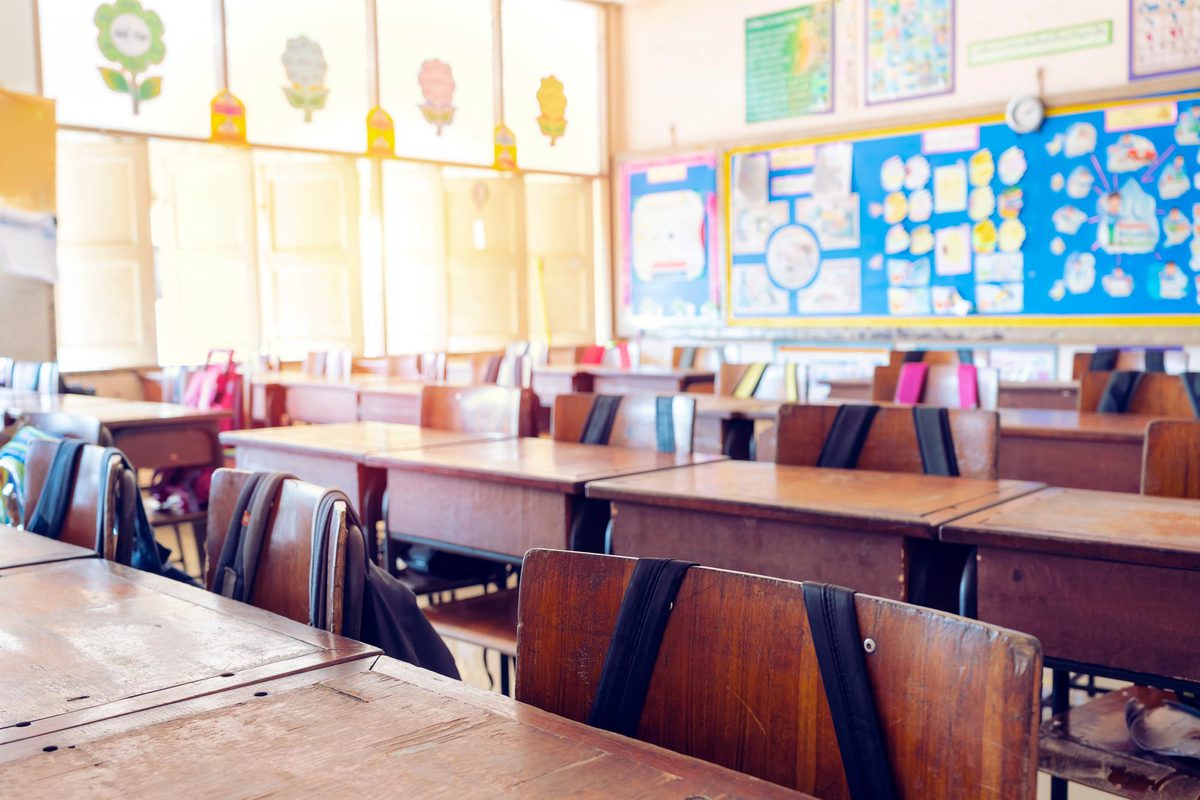 Wooden desks with backpacks hanging from the chairs