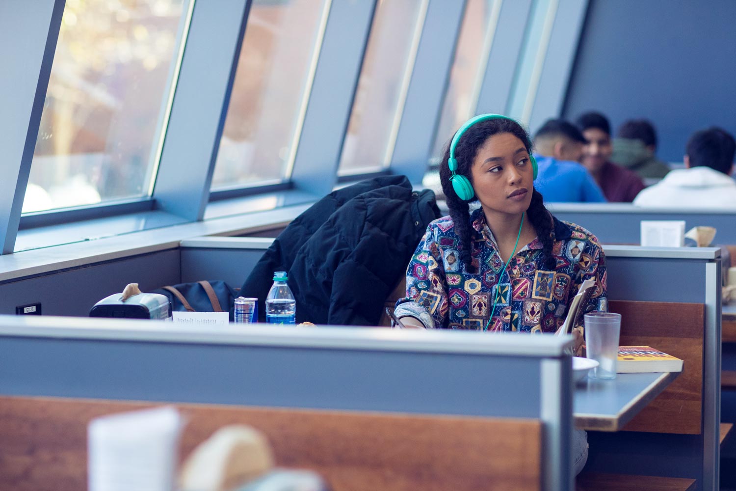 Student sitting at a dinning hall table wearing teal headphones
