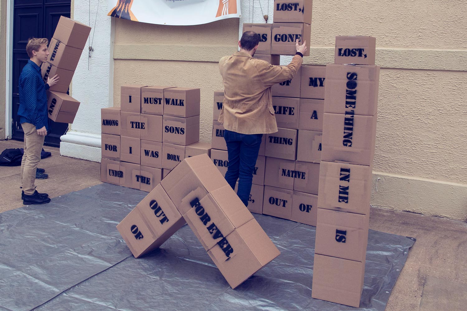 Timothy Schott, left stacking boxes with words on them creating a poem