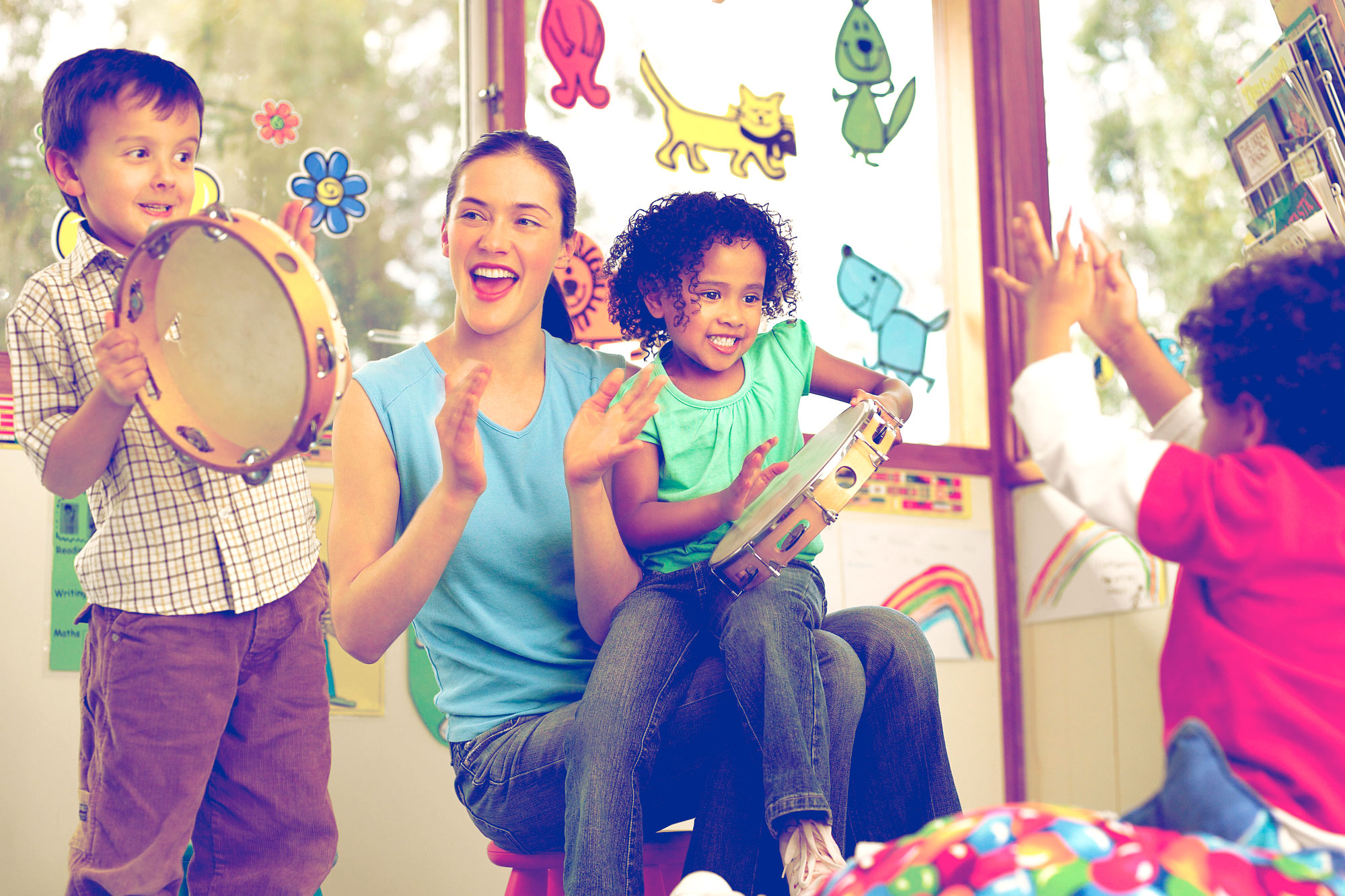 Teacher claps while children clap and play tambourines.