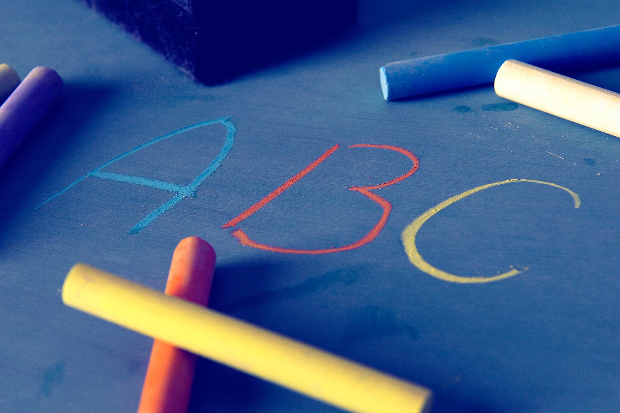 ABC written on a chalkboard with Blue, orange, and yellow chalk