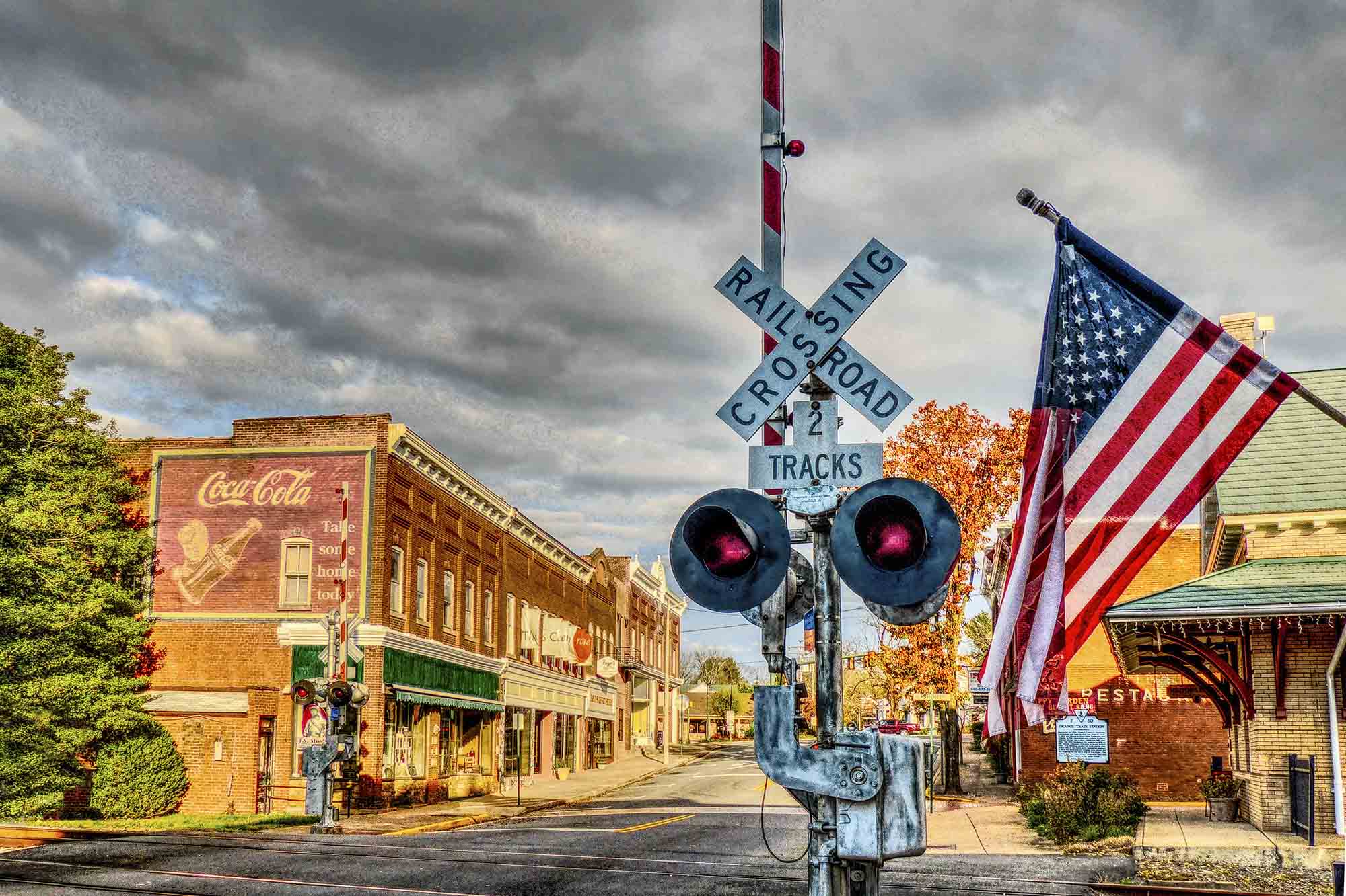 Railroad crossing sign in an old part of Charlottesville with an American flag next to the crossing