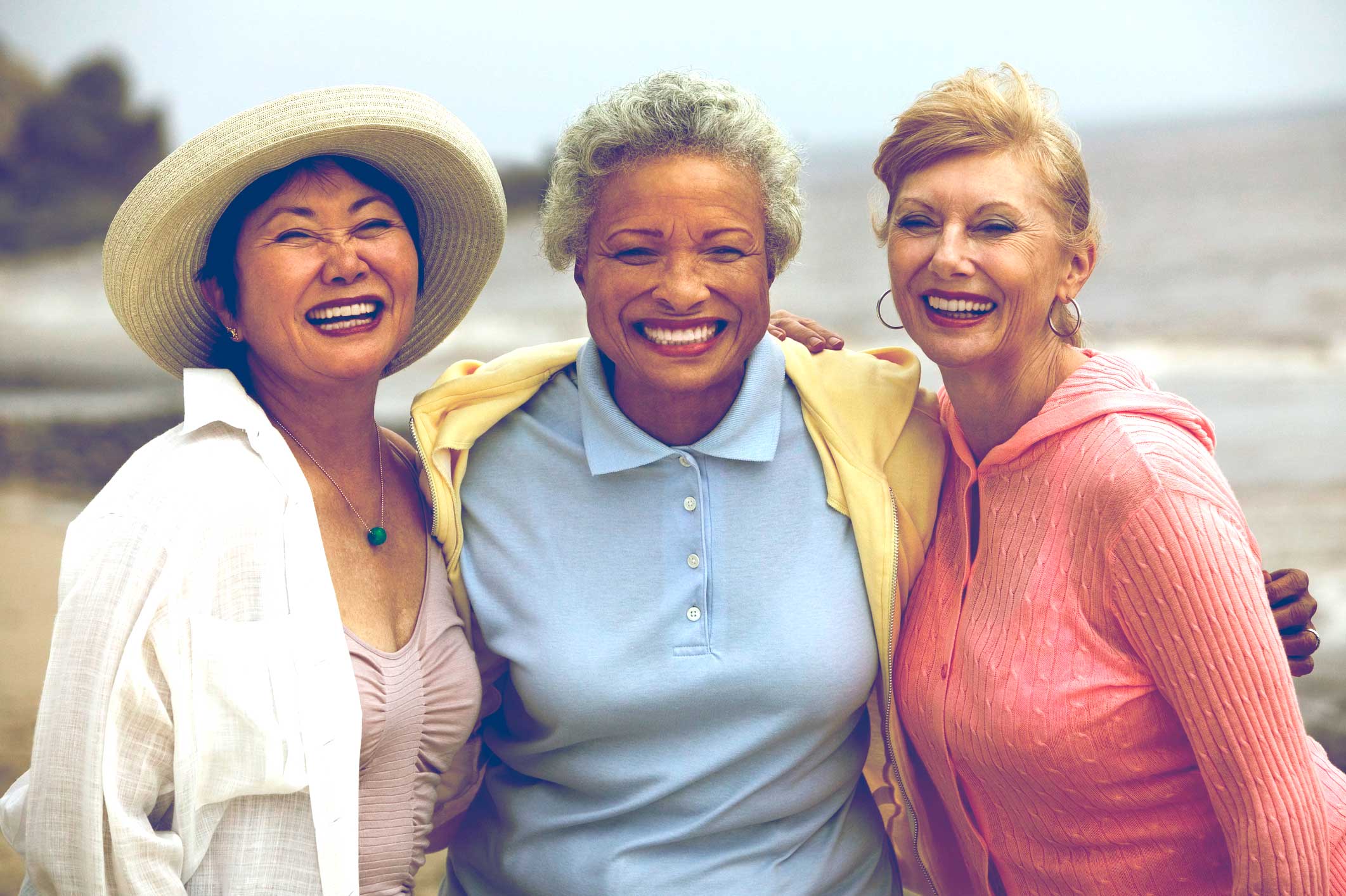 Three women wrapping their arms around each other laughing towards the camera