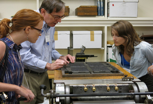 Students watch a man working on a rare book