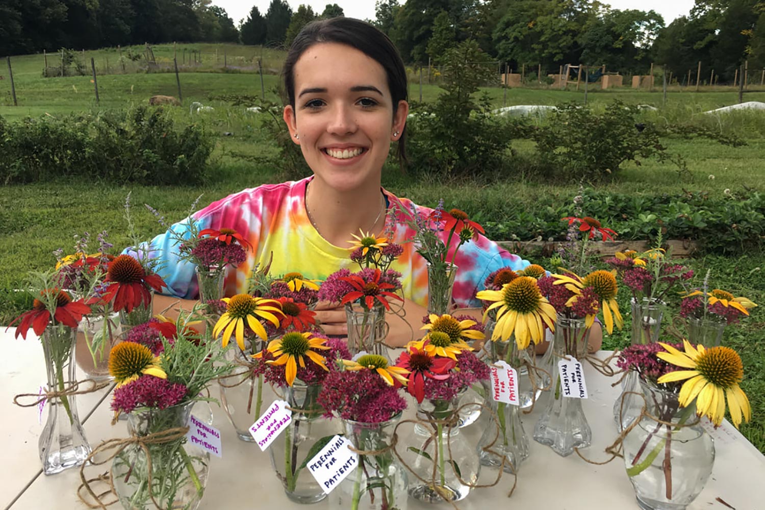 Reanna Panagides standing behind vases that have multi colored perennials in them