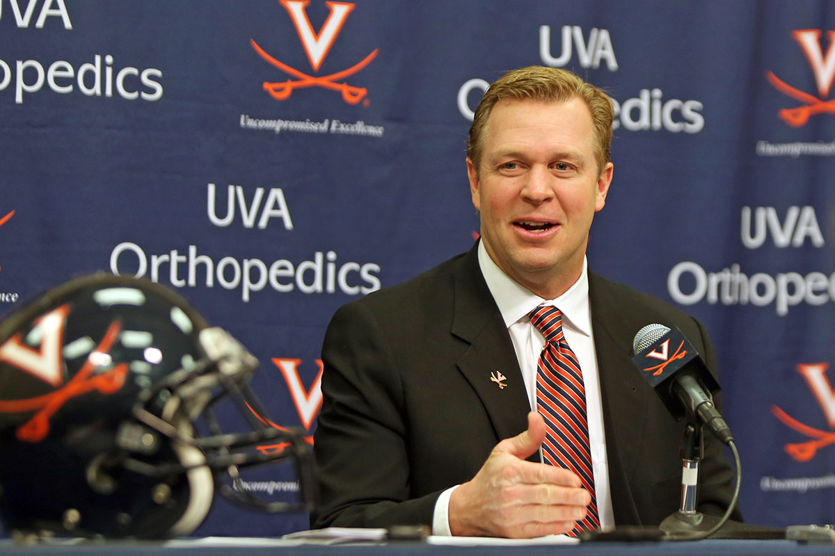 coach Bronco Mendenhall sitting at a table with a microphone giving a press conference