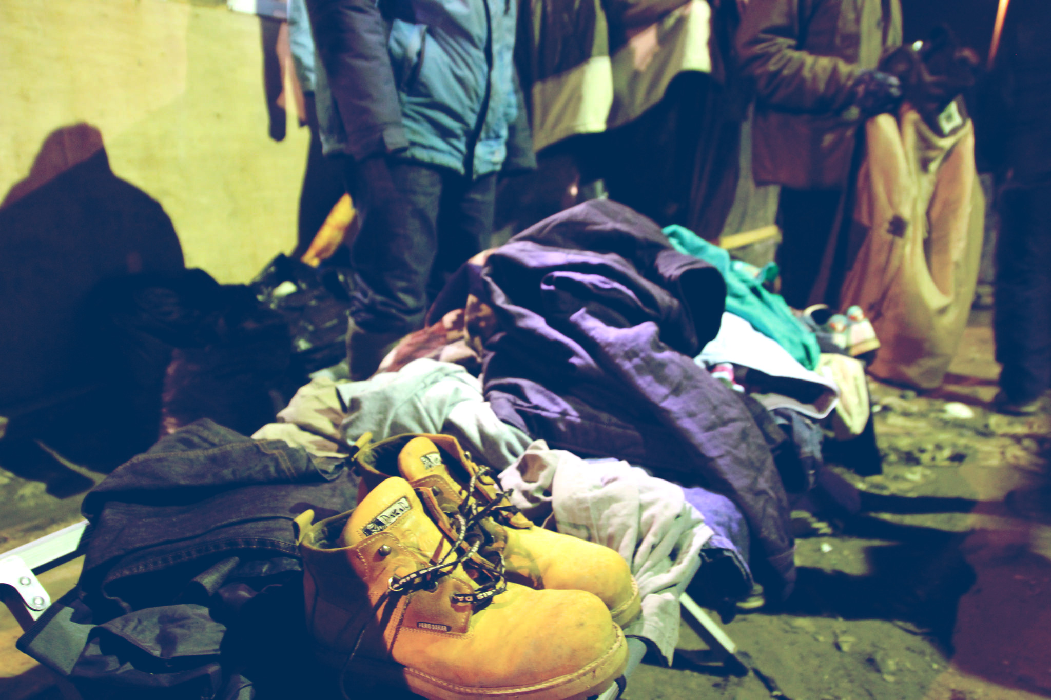 Shoes, jackets, and clothing stacked up in a pile on the ground