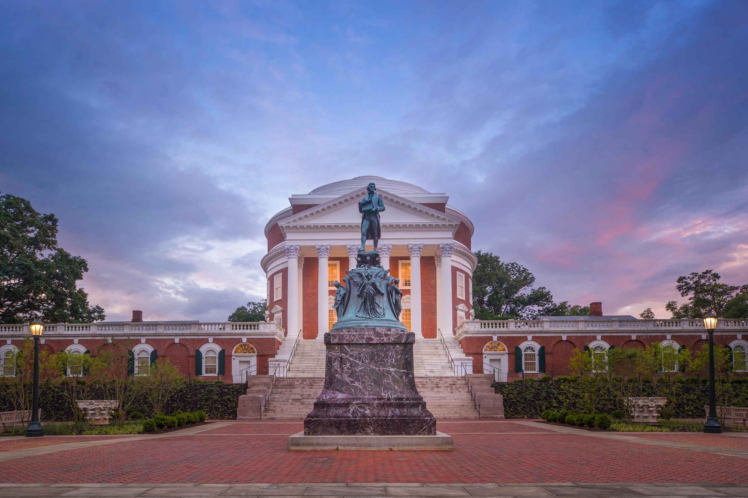 Thomas Jefferson statue in front of the Rotunda with a blue, purple, and pink clouds