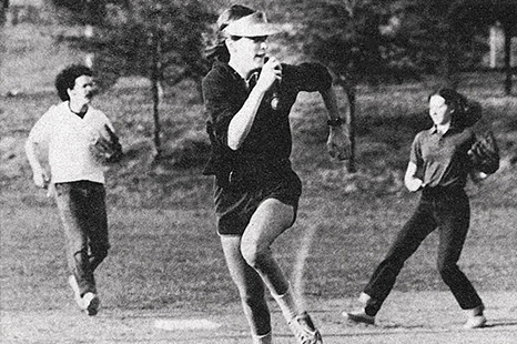 black and white image of a woman running a base during a softball game
