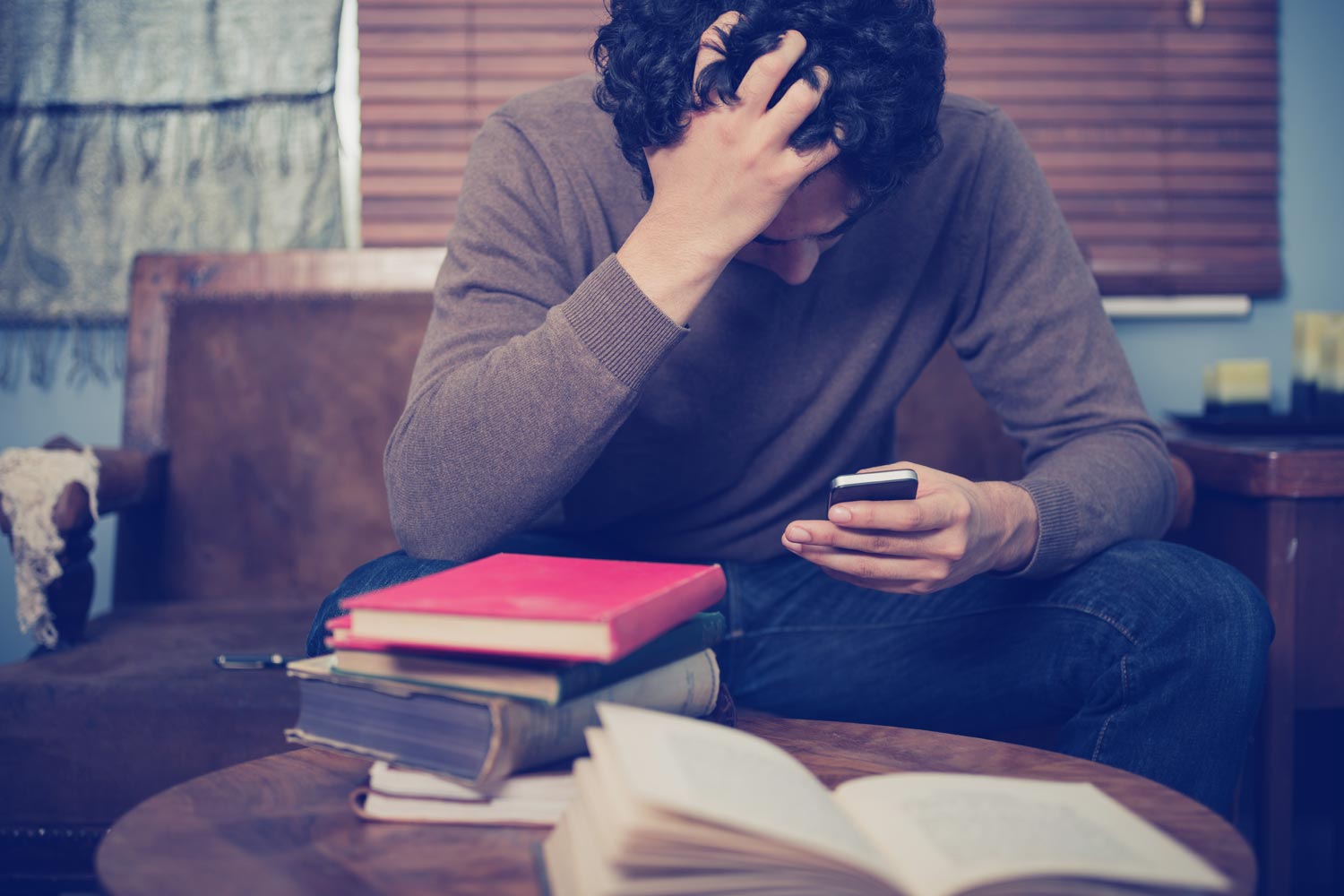 Person holding a phone and has one hand on his head