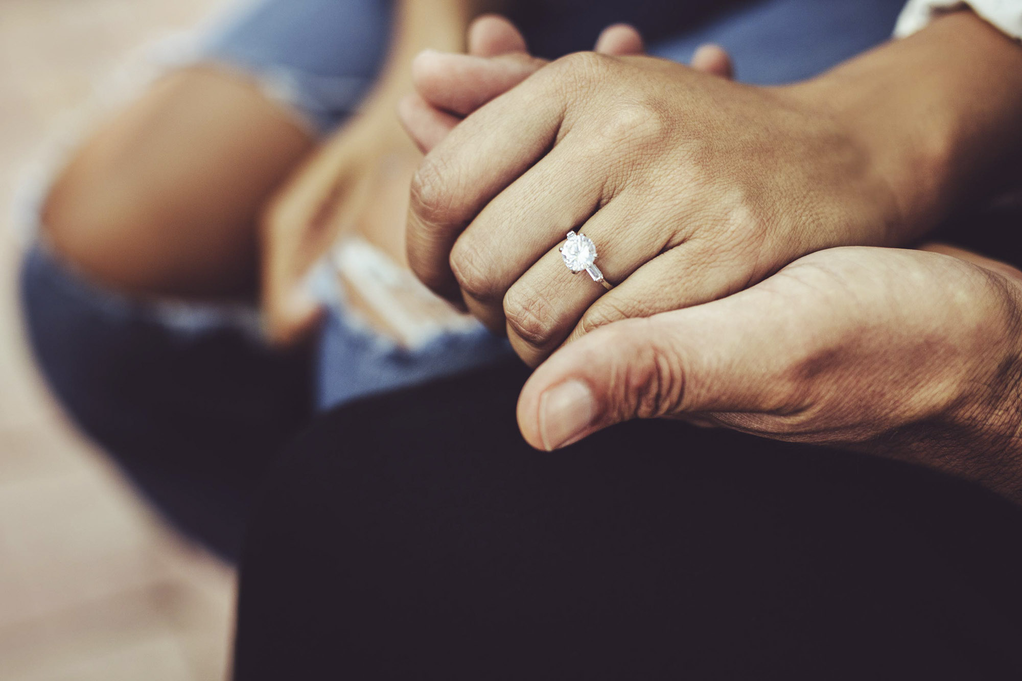Man and woman holding hands with the woman's diamond ring visible