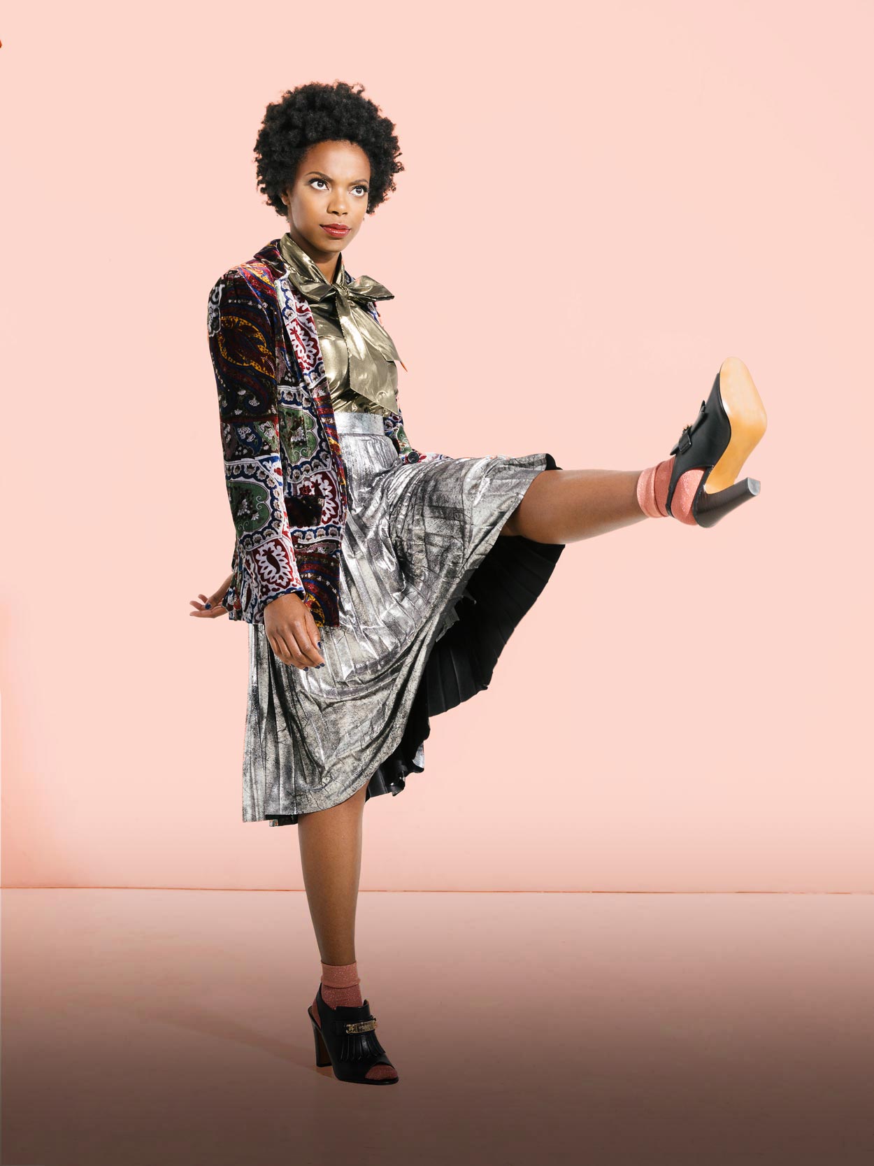 Sasheer Zamata stands on one leg with the other high in the air
