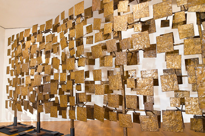 Sculpture of hundreds of various sized squares from a shine gold brown color hanging down.  Squares are overlapping and not overlapping there is no pattern