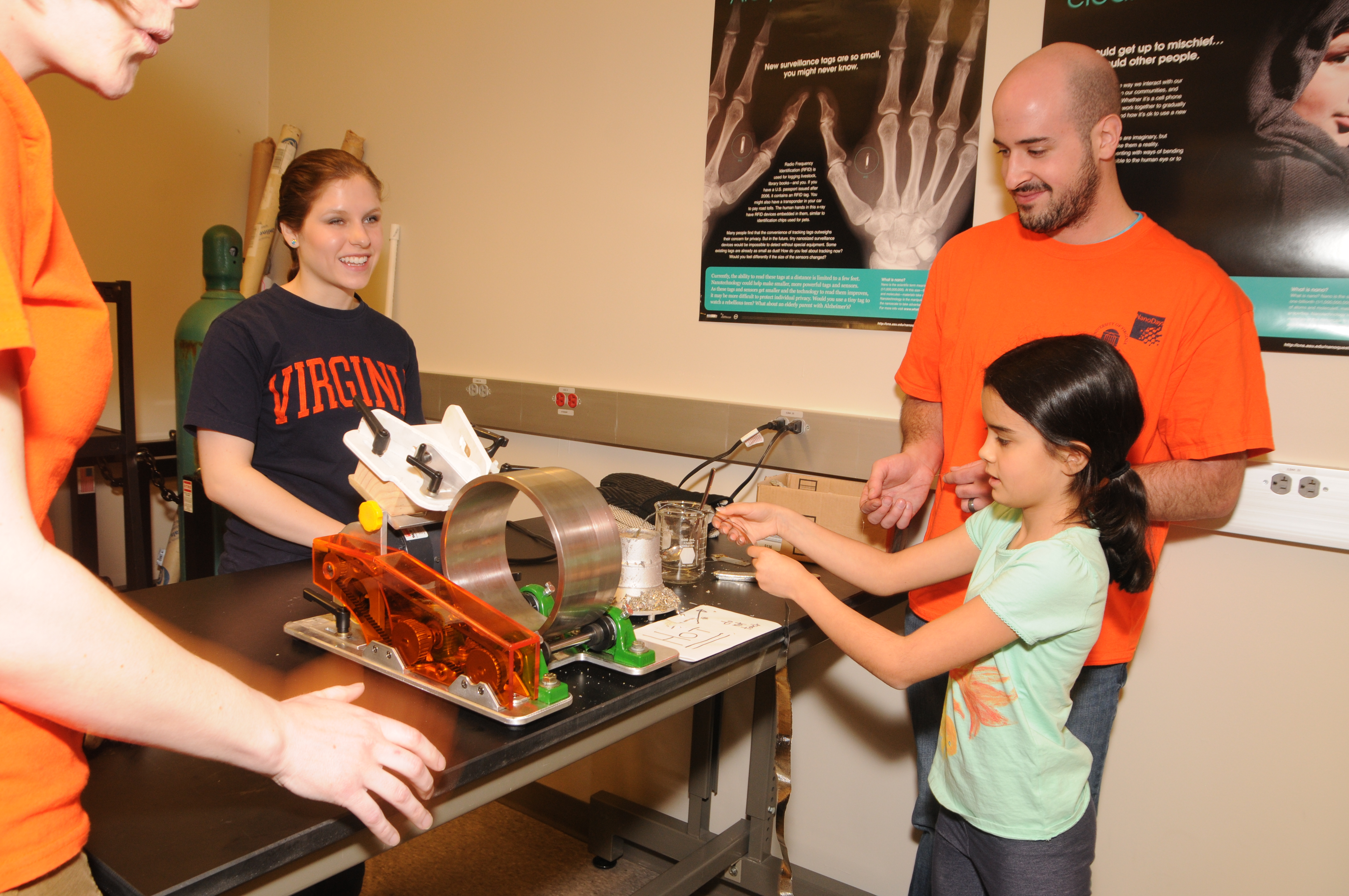 A small child works with a hands on engineering project while UVA students watch