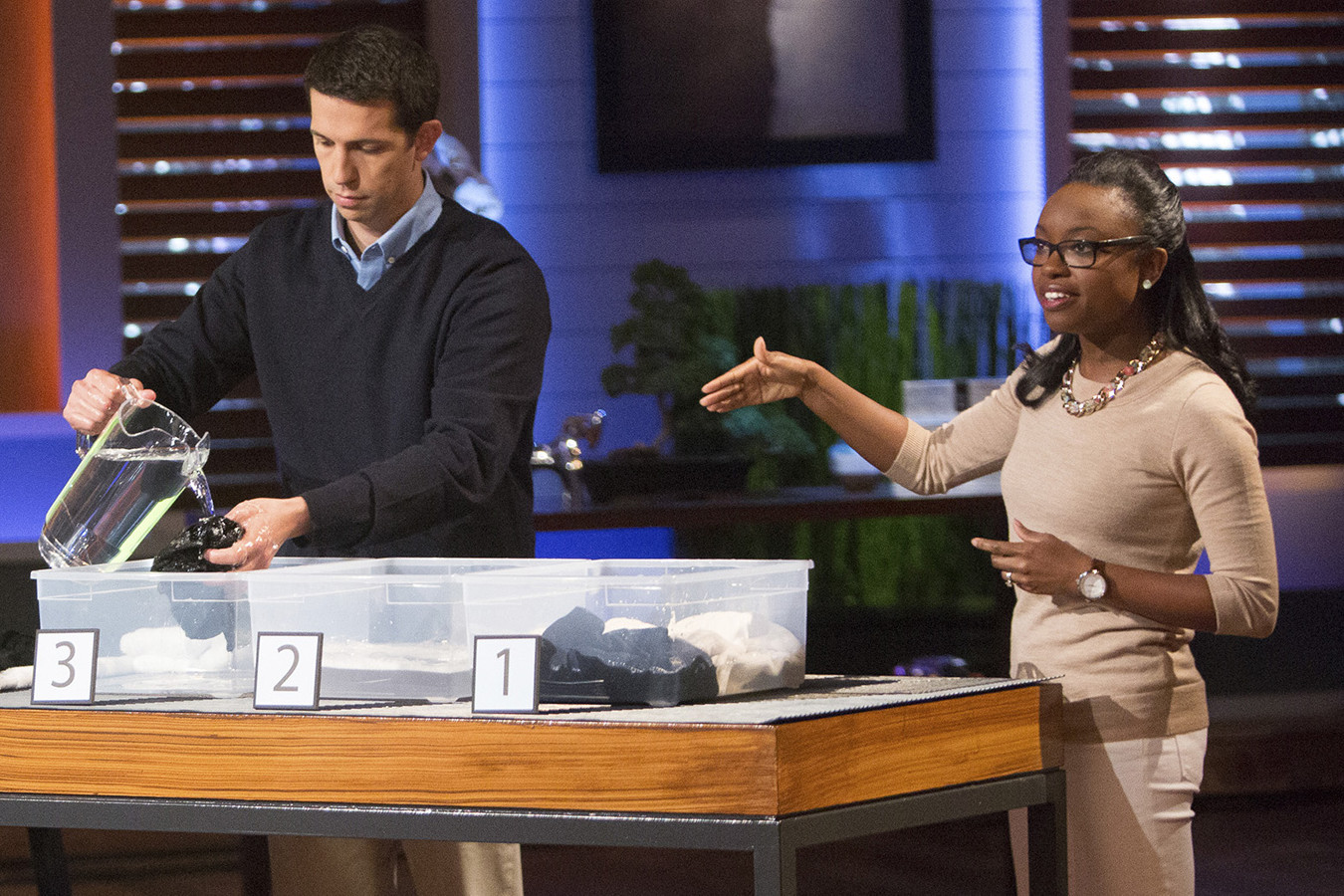 Desirée Davis Stolar, right, talks to the Sharks on Shark tank while a man next to her pours water onto clothing