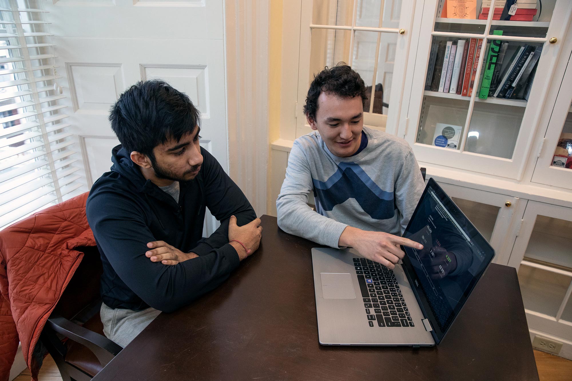 James Yun and Soukarya Ghosh sit at a table together and look at a laptop