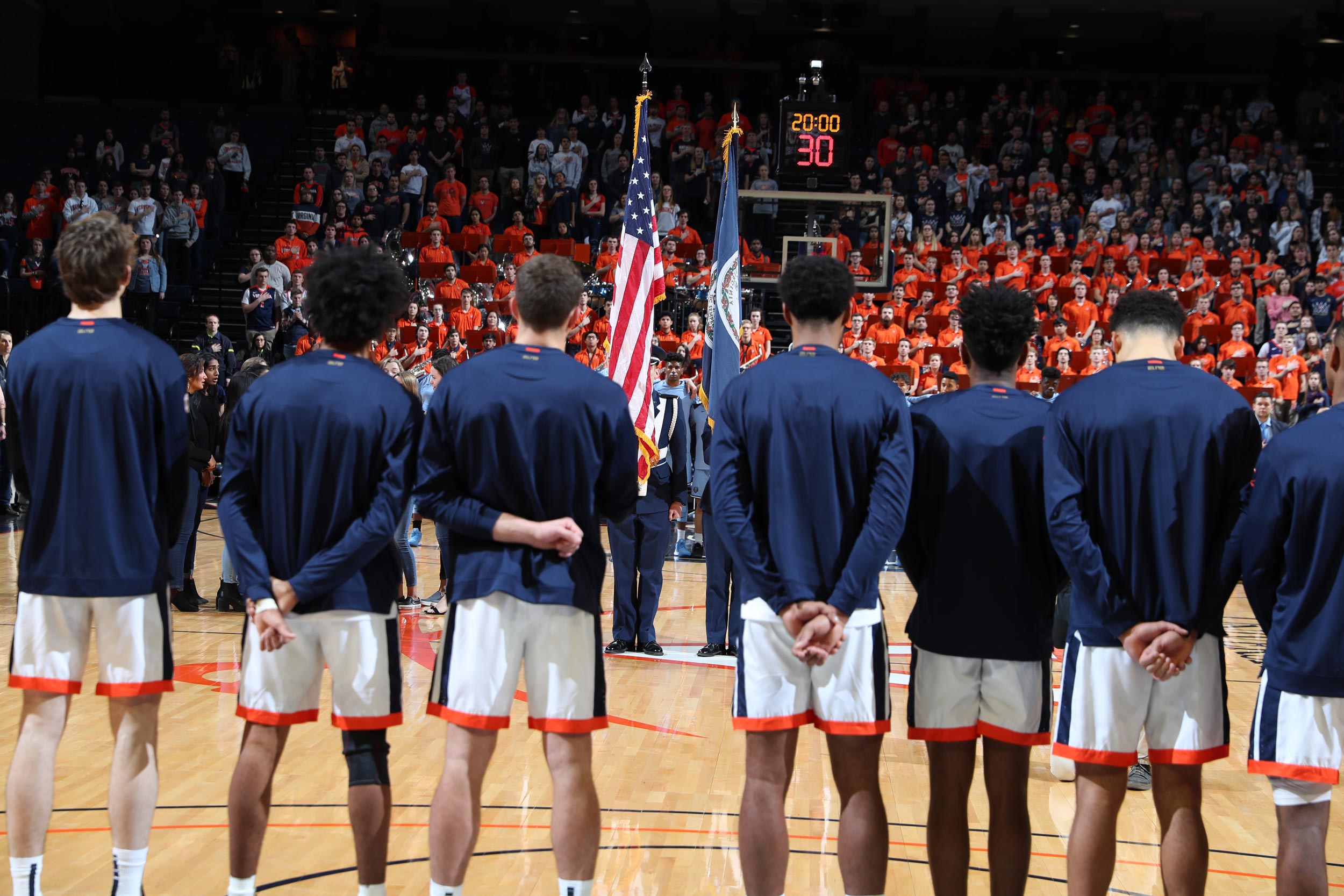UVA mens basketball team standing facing the USA flag 