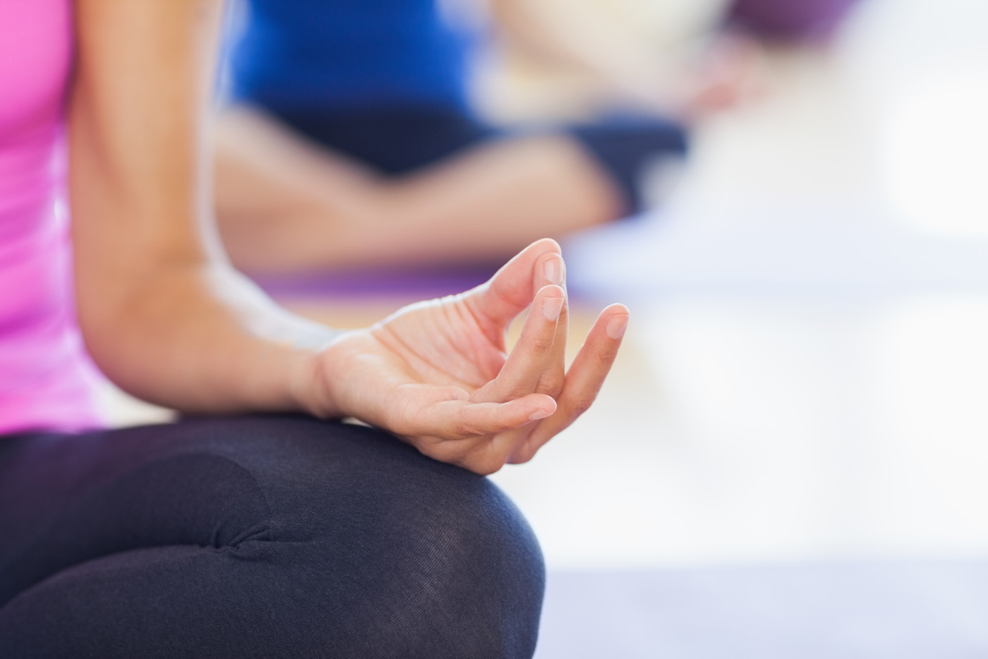 Woman meditating with her hand on her knee with her thumb and middle finger touching