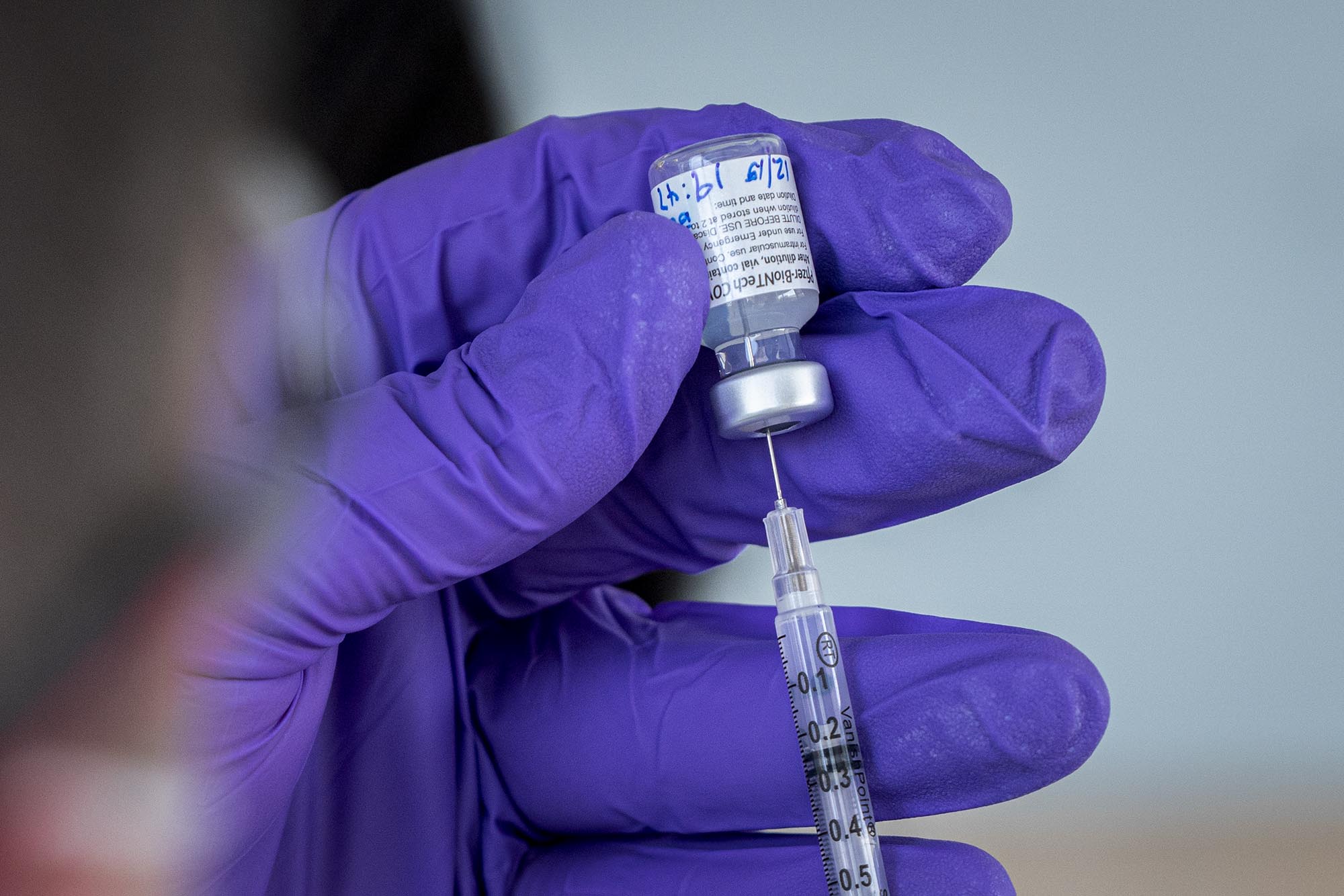 Healthcare professional drawing up a vaccine into a syringe 