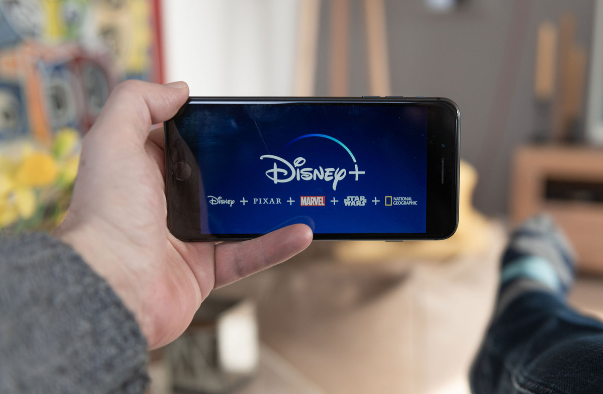Person holding a phone that had the Disney + logo in the middle and the following horizontal underneath: Disney  + Pixar + Marvel + Star Wars + National Geographic